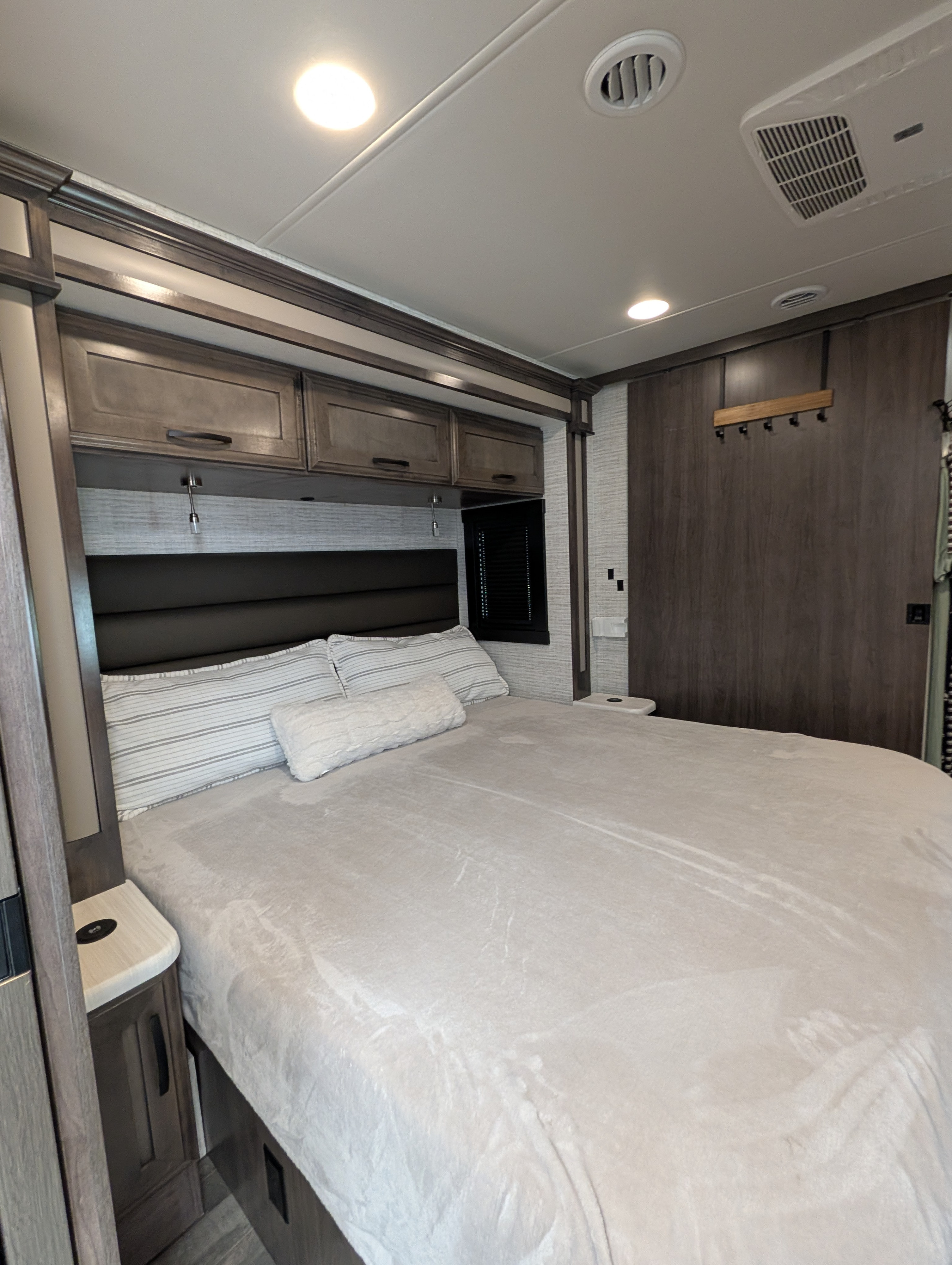 This modern RV rental bedroom offers comfort with a queen bed, overhead storage, and ceiling AC, ideal for restful travels.. Jayco Precept 2025