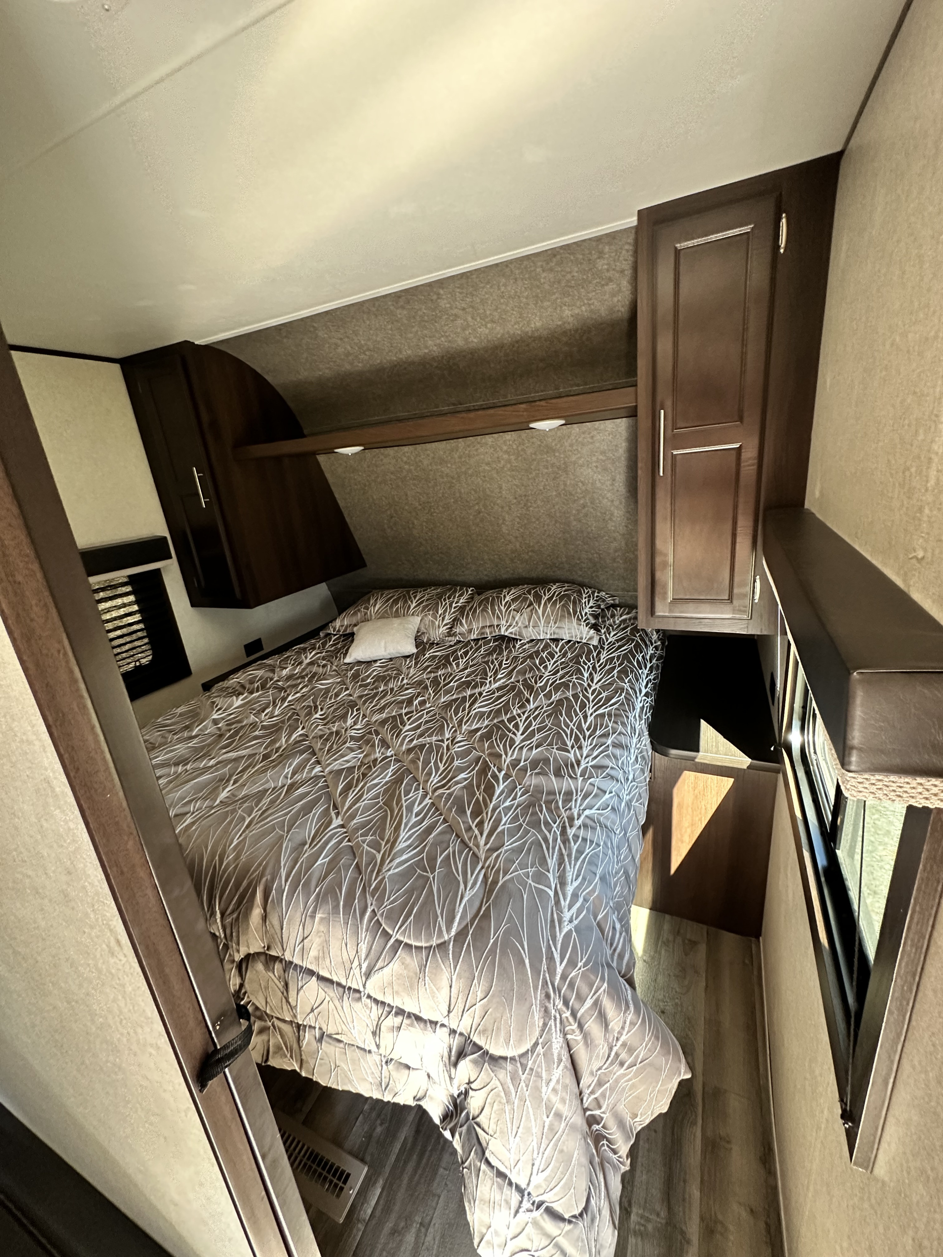 RV rental bedroom featuring a tree-patterned comforter, compact design, and ample overhead storage for travel comfort.. Jayco Jay Flight 2020