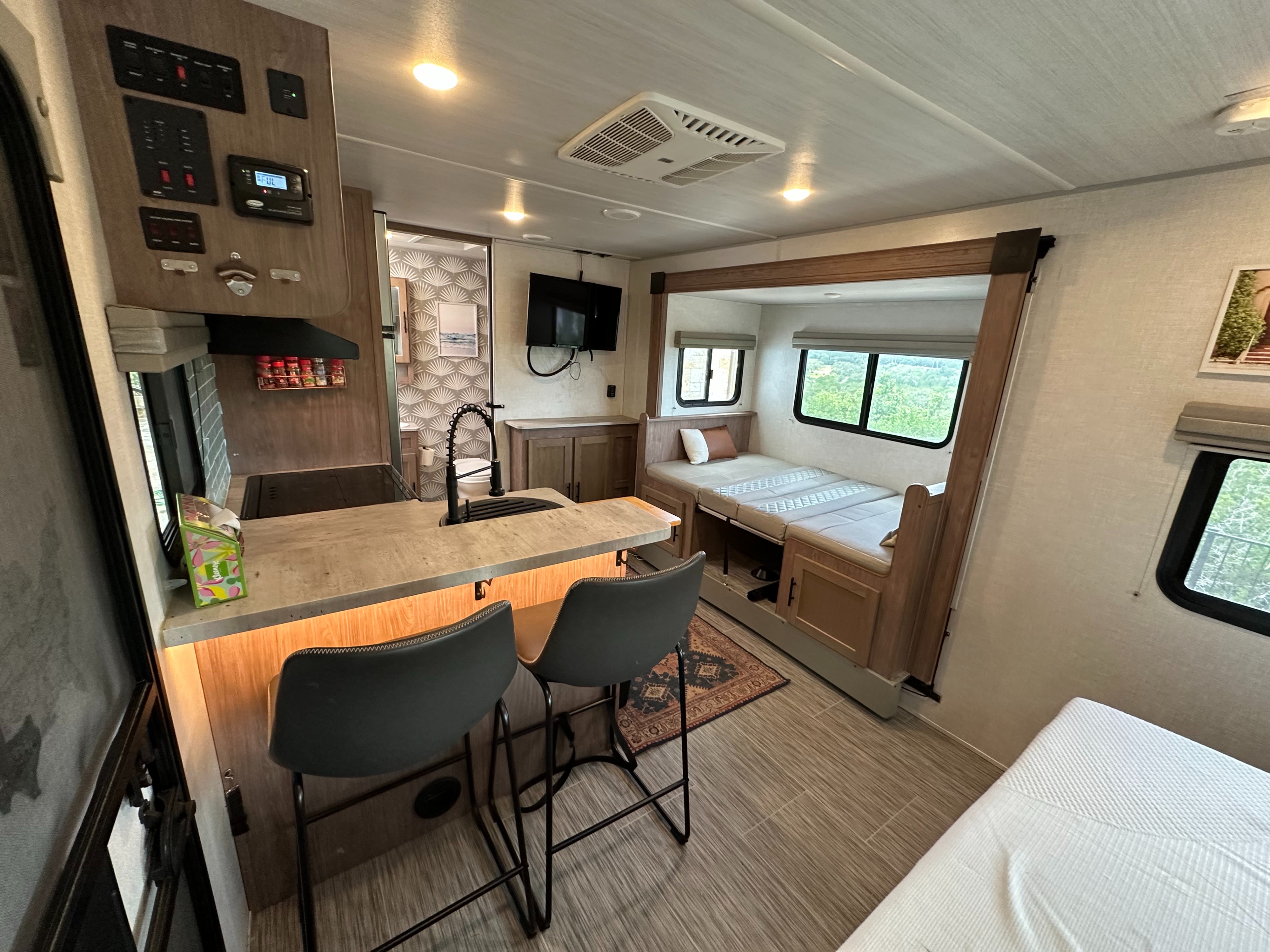 RV rental interior showing a bright kitchenette with bar seating and a compact bunk bed/lounge area.. No Boundaries 20 2022