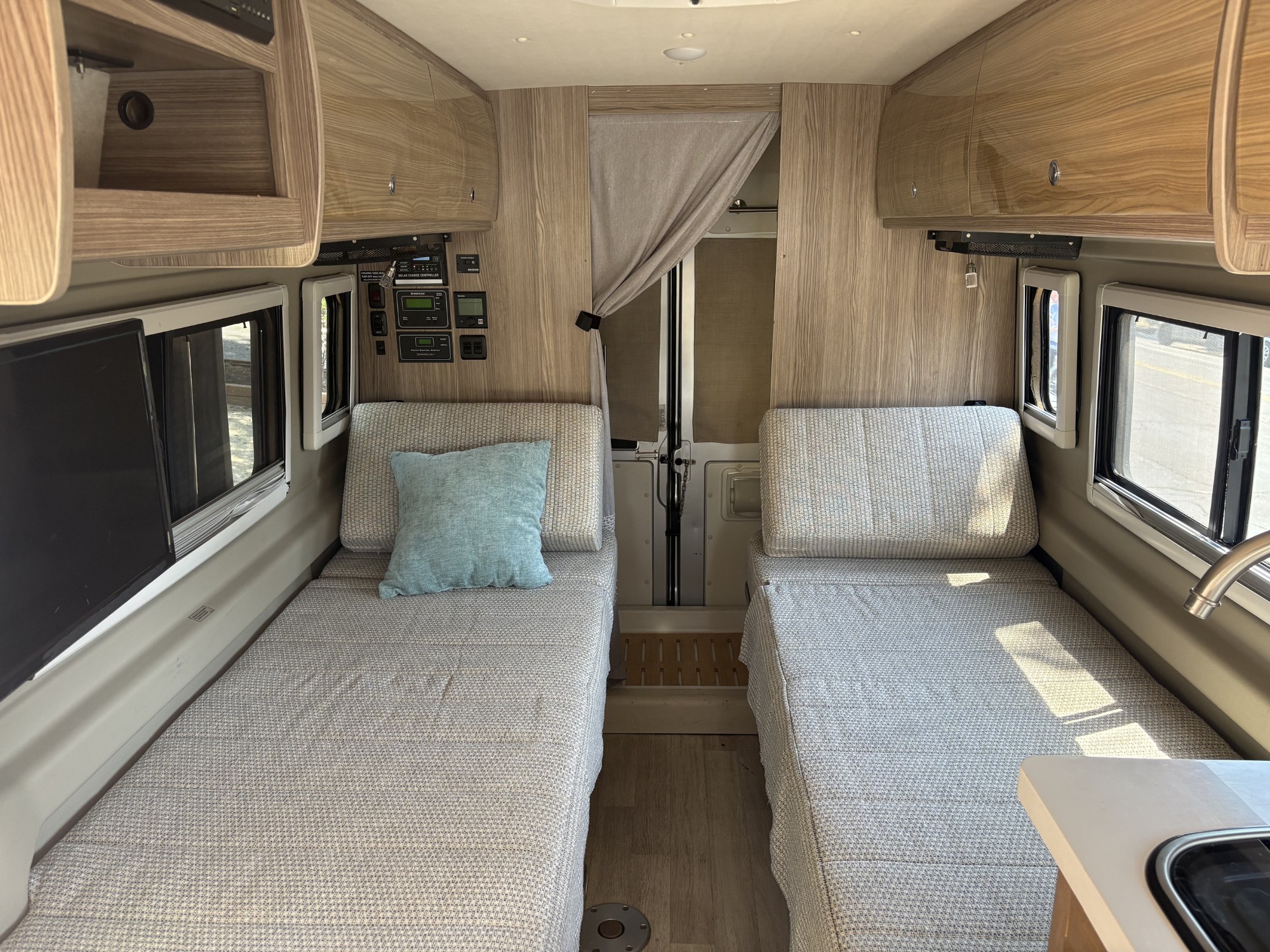 RV rental interior features twin beds with patterned bedding, overhead storage, and control panels for your journey.. Winnebago Travato 2021
