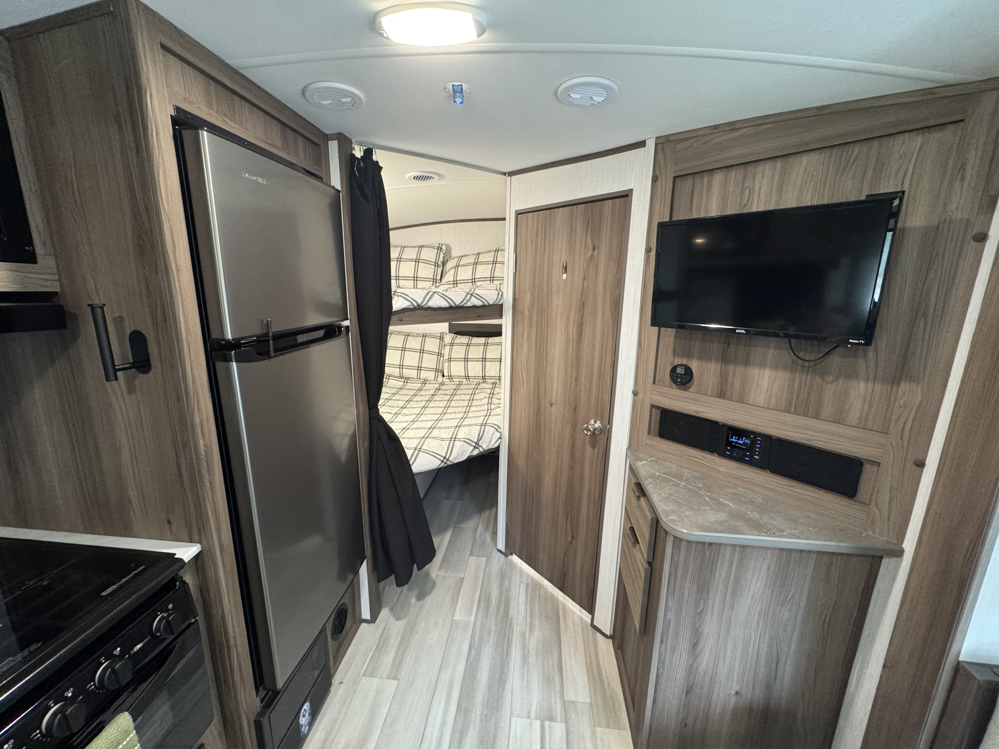 Explore this RV rental's interior: modern kitchen, cozy bunk beds, and a compact entertainment setup with TV.. Cruiser RV MPG 2023
