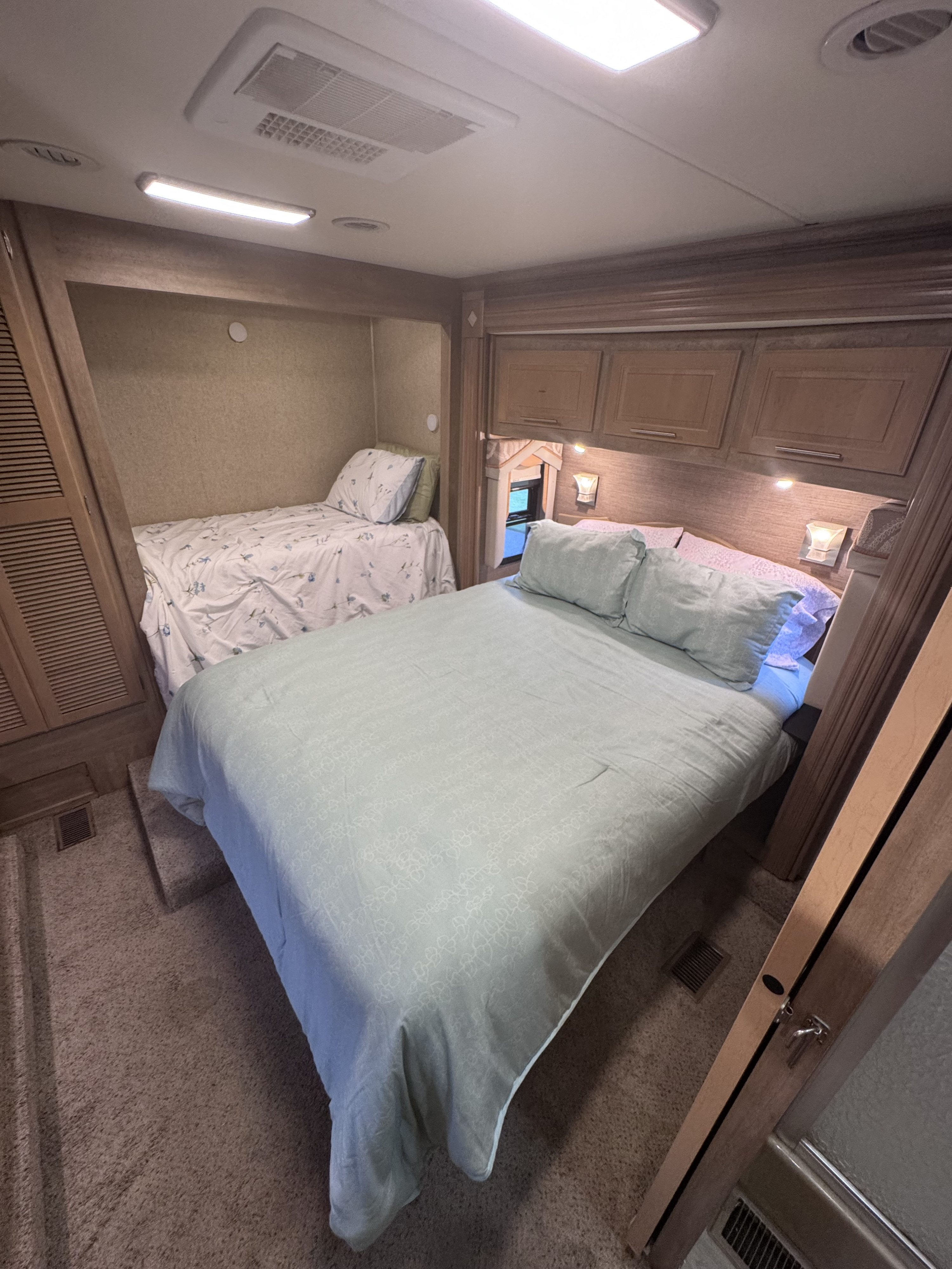 An inviting RV rental bedroom, offering a primary bed and a cozy bunk bed, perfect for family adventures on the road.. Forest River Coachmen Pathfinder 2014