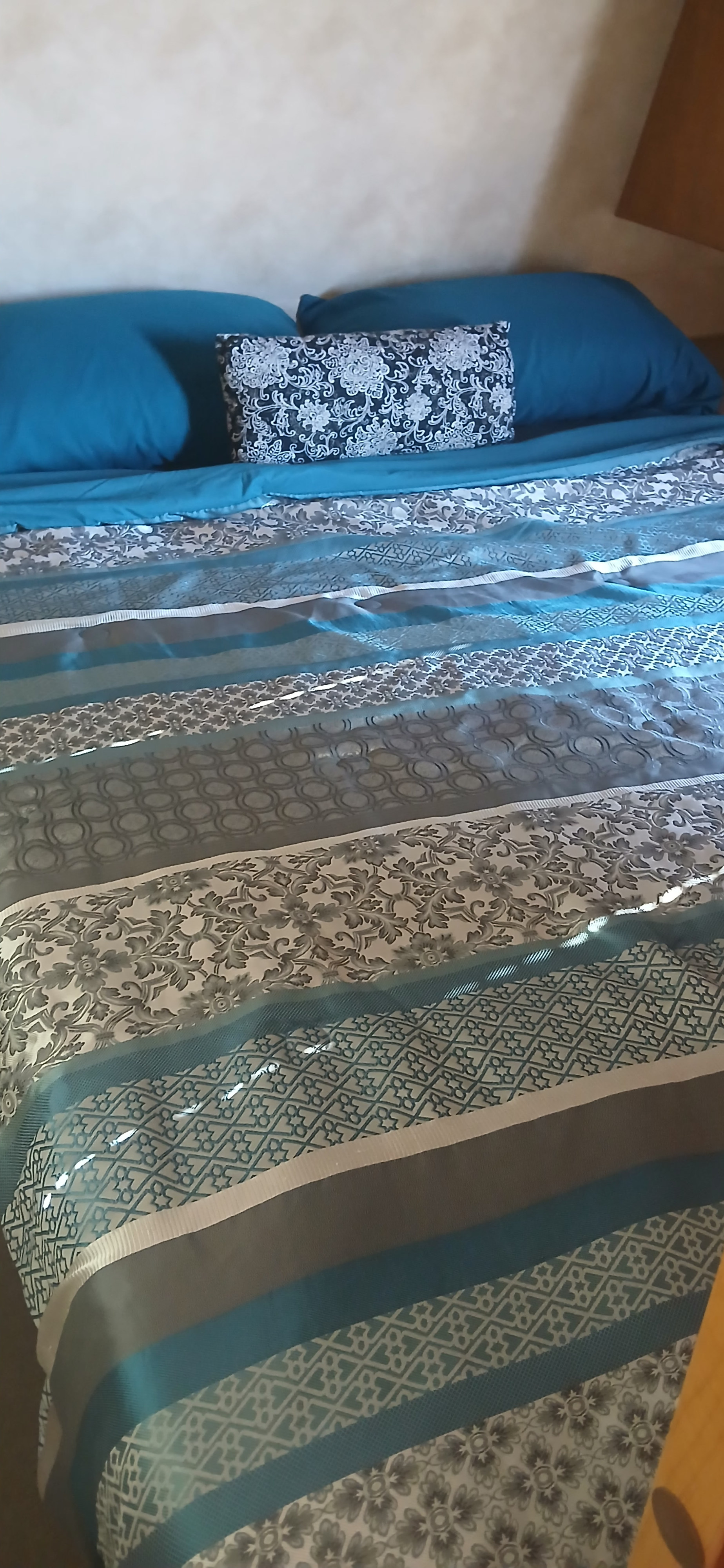 RV rental bed with vibrant teal and grey patterned bedding, including decorative pillows, ready for a restful journey.. Palomino Puma 2013