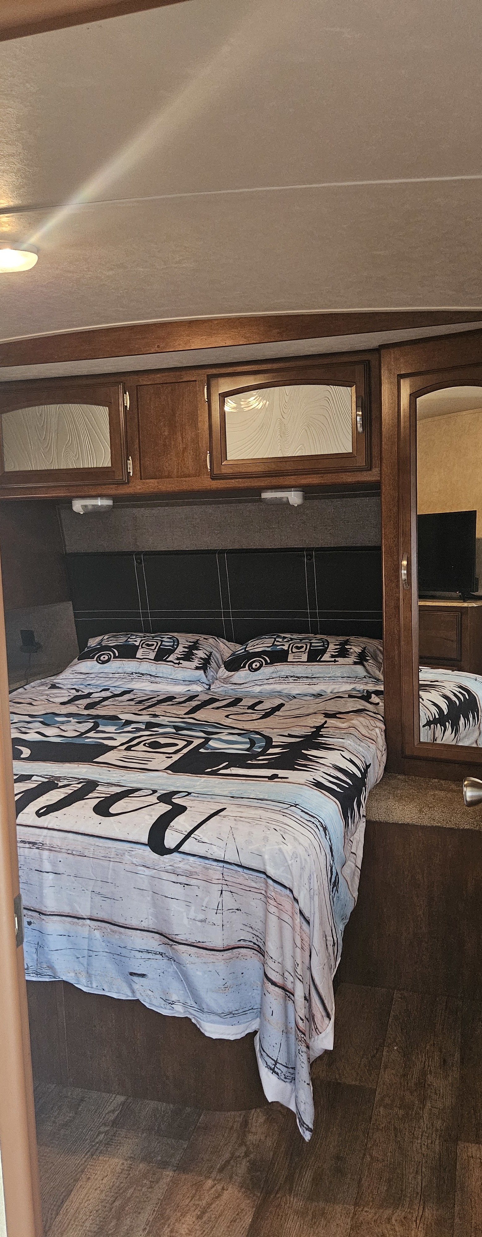 Relax in this inviting RV rental bedroom. Features a comfy themed bed, overhead cabinets, and wood-look floor.. Forest River Salem 2016