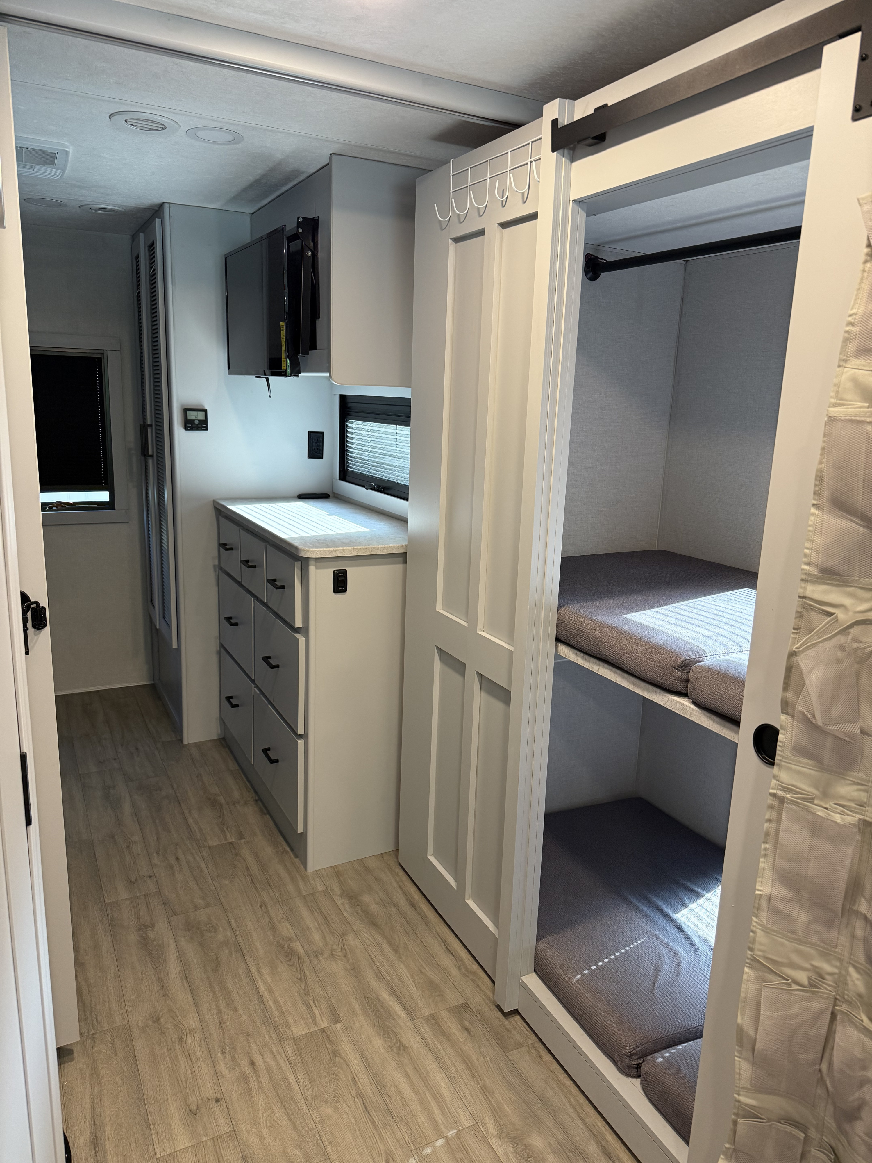 Compact rv rental with modern interior: bunk beds, dresser, TV, and light wood flooring.. Forest River Coachmen Pursuit 2025