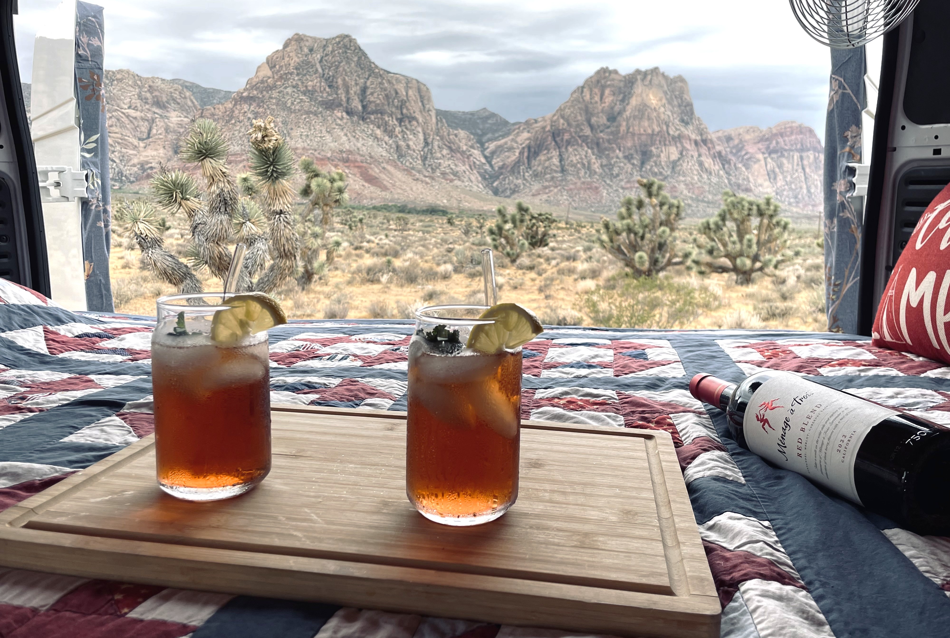 Cozy rv rental scene: two iced drinks, wine, & a patriotic quilt, overlooking a majestic desert mountain view with Joshua trees.. Dodge Other 2021