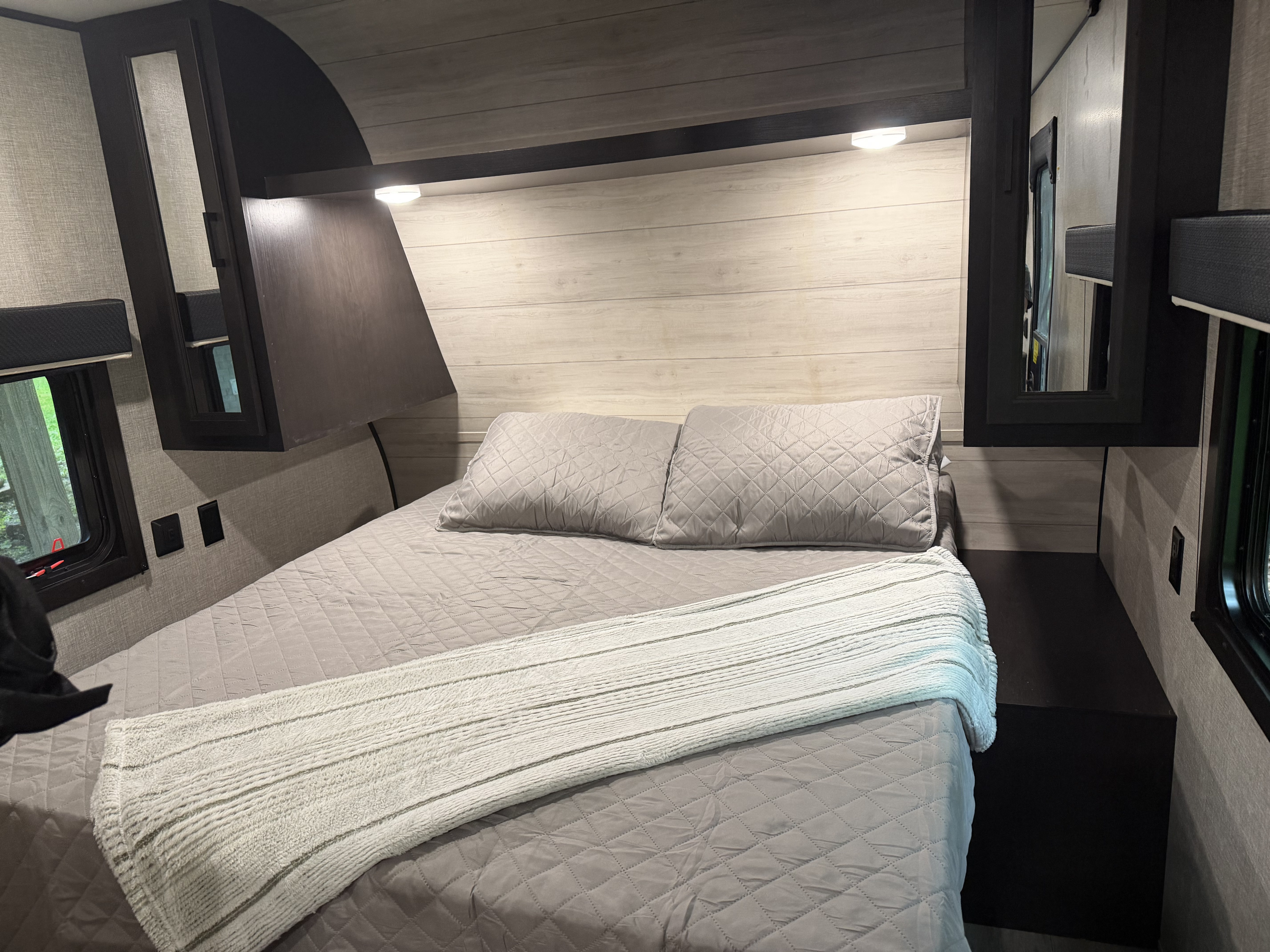 Comfortable RV rental bedroom featuring a cozy bed with quilted bedding, built-in storage, and ambient lighting.. Jayco Jay Flight SLX 2022