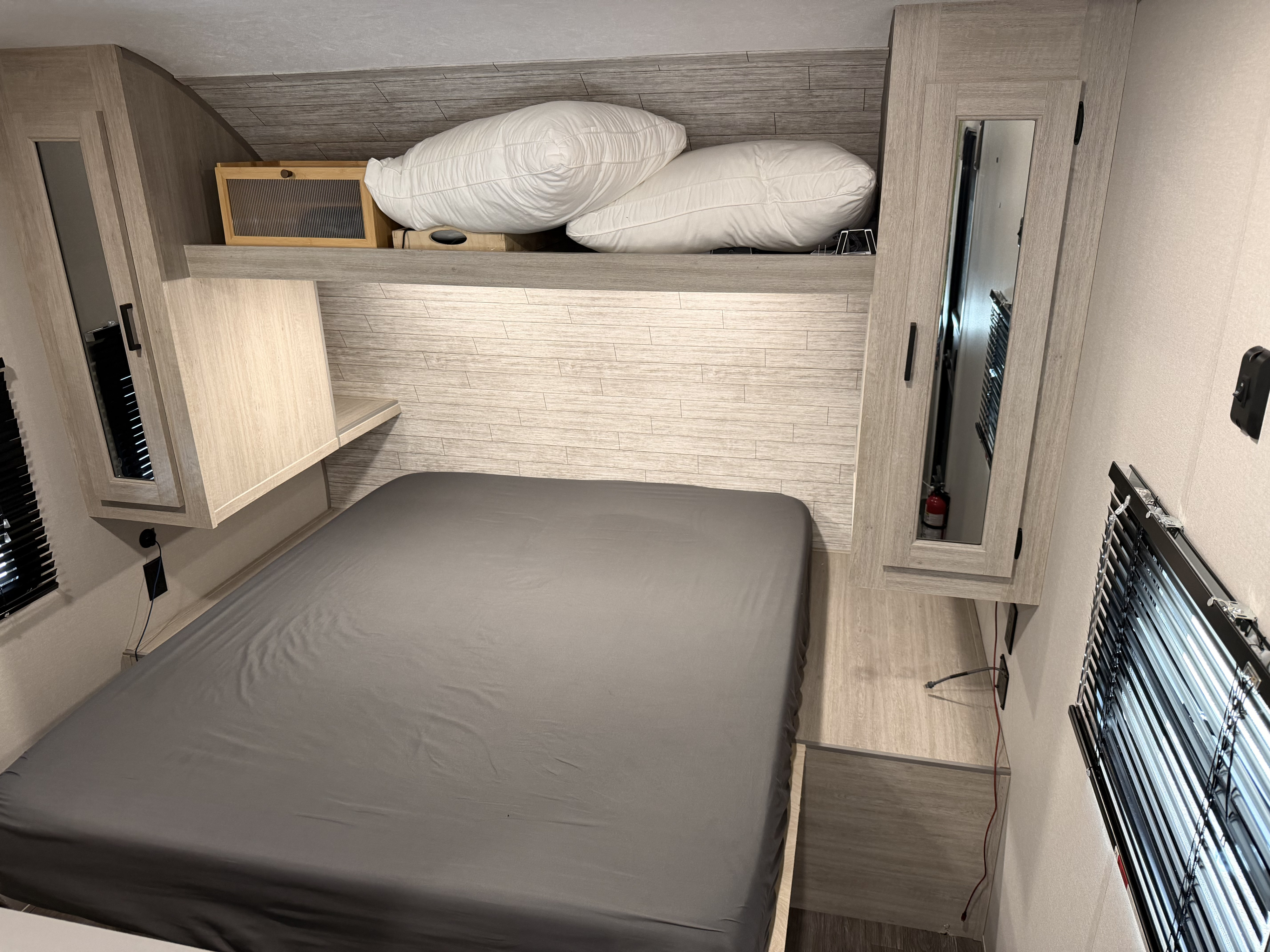 Modern RV rental bedroom with gray bed, built-in storage, and window blinds. Ideal for comfortable travel.. Forest River Aurora Aurora Light 2026