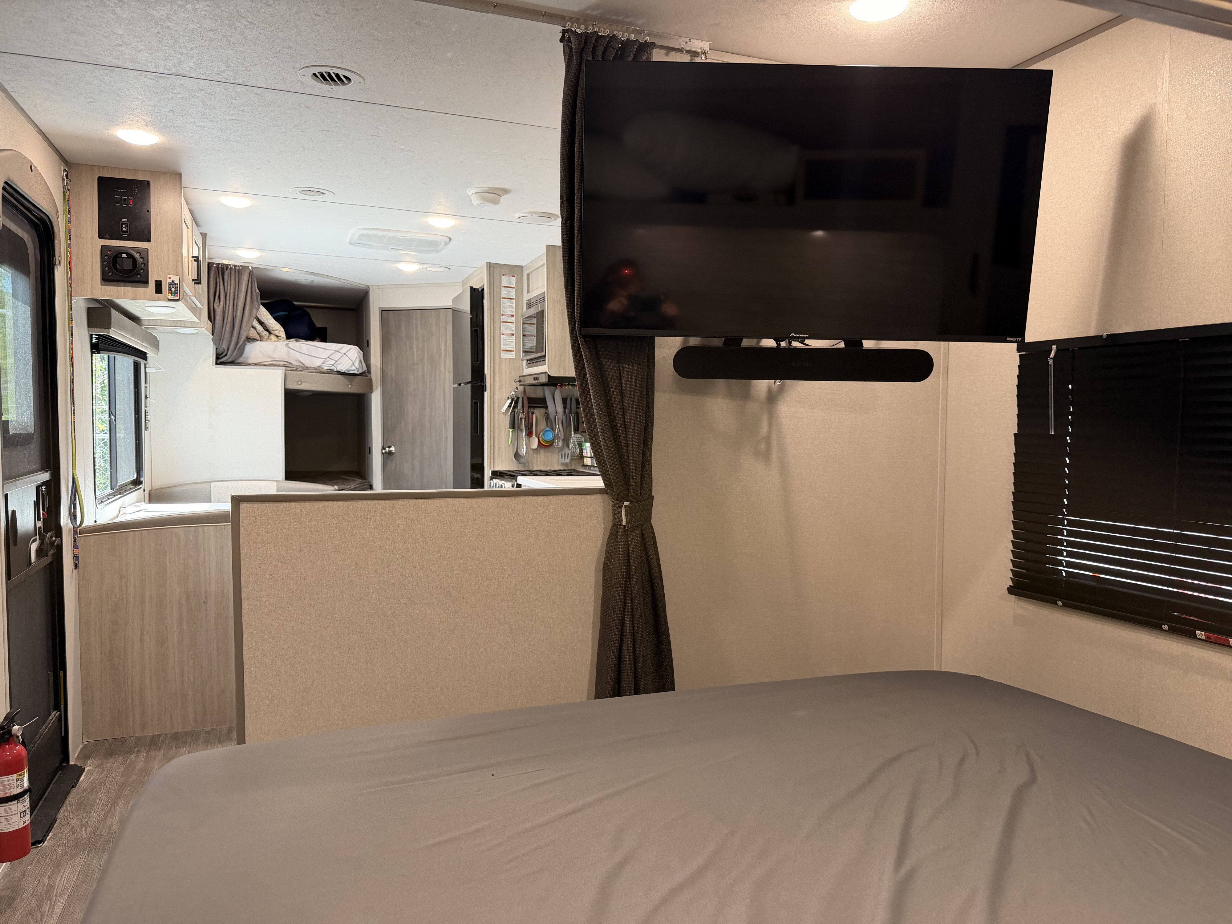 RV rental: Cozy interior from the bed, showing wall-mounted TV, kitchen, and bunk beds. Fire extinguisher by door.. Forest River Aurora Aurora Light 2026