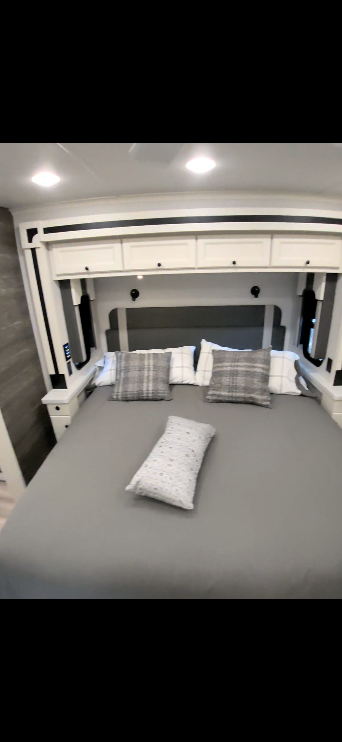 RV rental bedroom featuring a modern bed with gray bedding, overhead cabinets, and practical built-in nightstands.. Allegro Allegro Open Road 2026