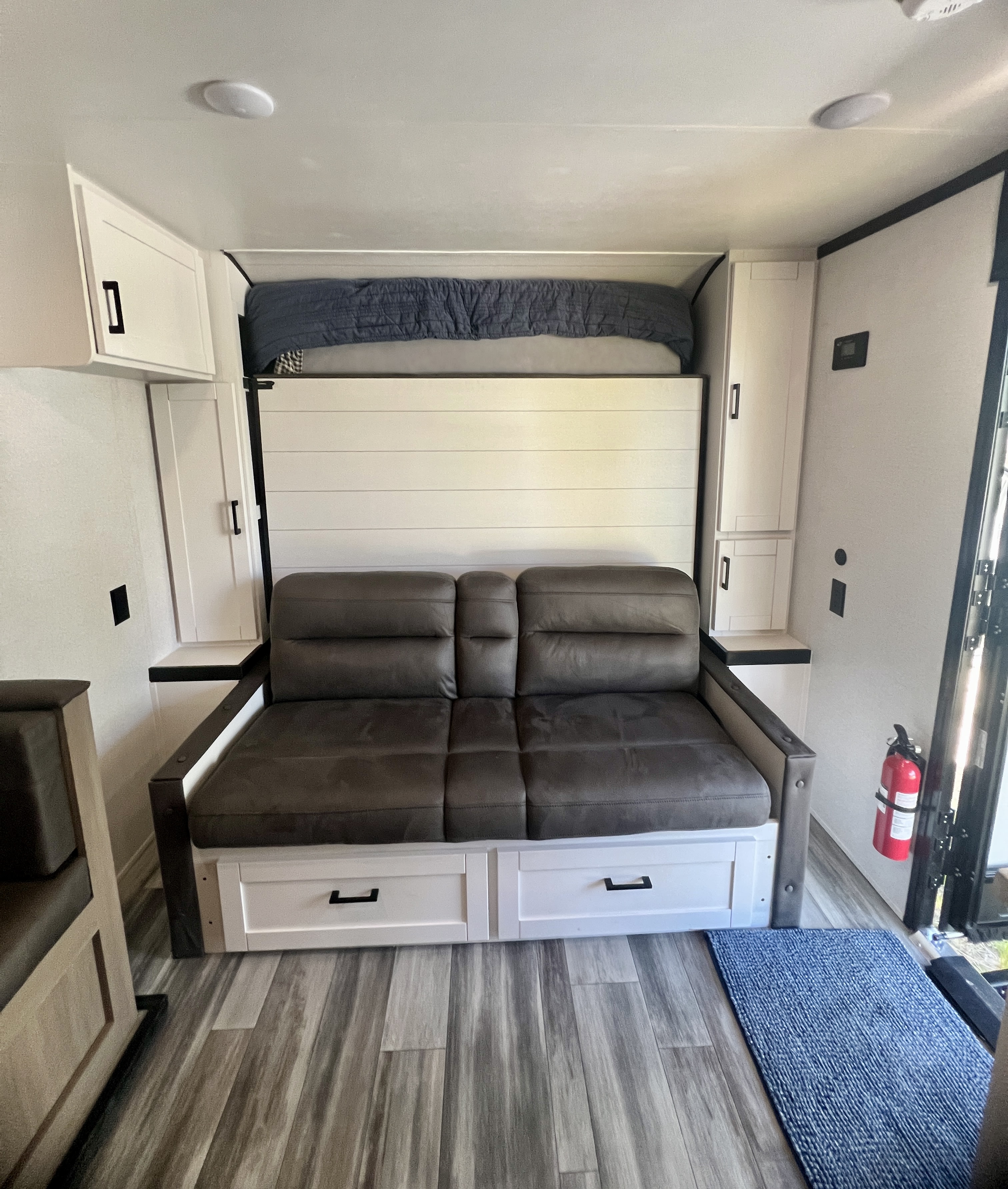 Bright rv rental interior with a grey convertible sofa, overhead bed, and white cabinets. Modern and space-saving design.. 1UBC0AK9T7ZF0106 197MBW Jay Flight SLX TT 2026
