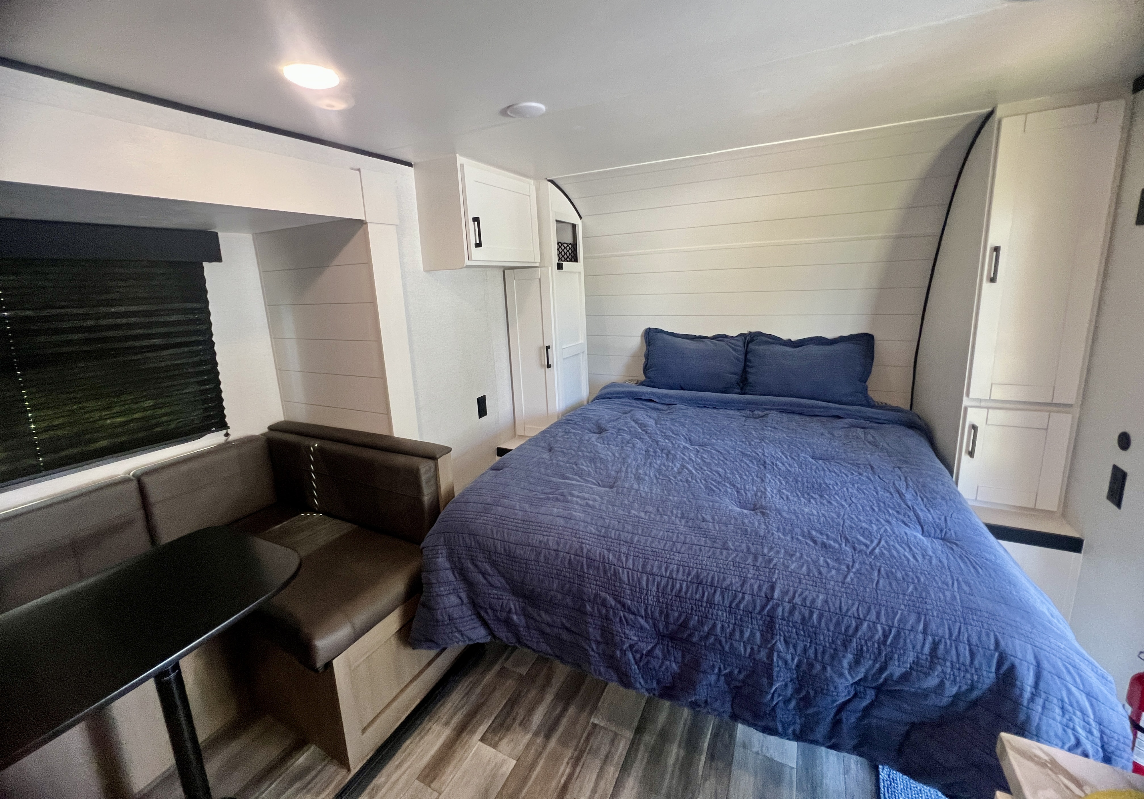 RV rental interior: Compact bedroom & dinette, featuring modern shiplap walls and a cozy blue bed.. 1UBC0AK9T7ZF0106 197MBW Jay Flight SLX TT 2026