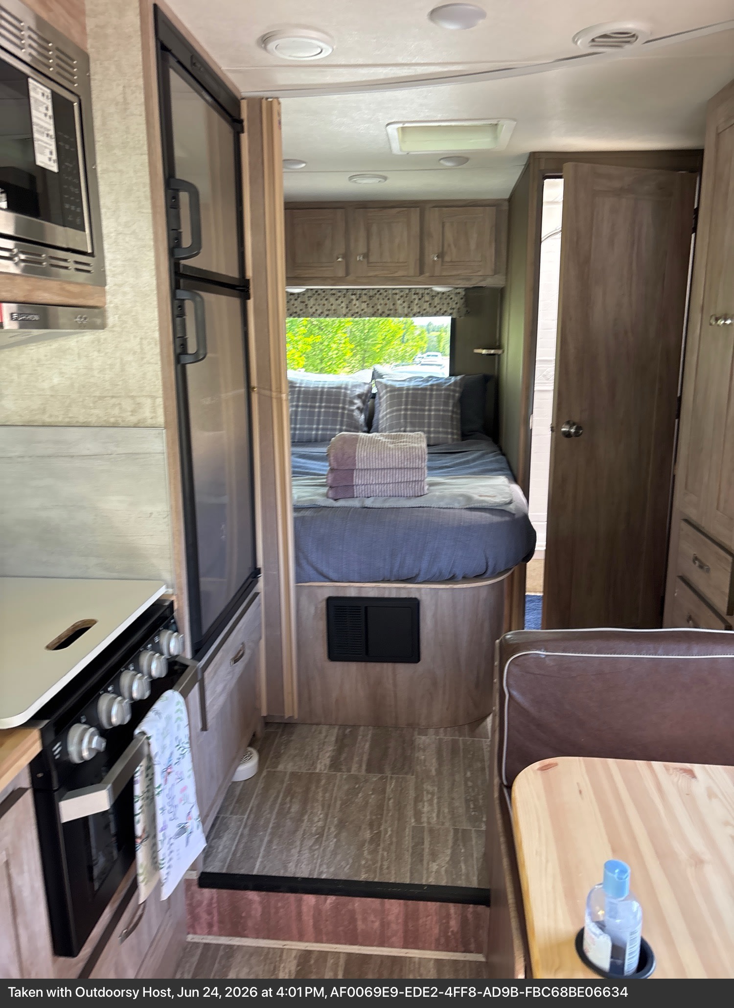 Cozy rv rental interior: kitchen with microwave, stove, fridge, dinette, and a comfy bedroom with a window view.. Forest River Sunseeker LE 2020