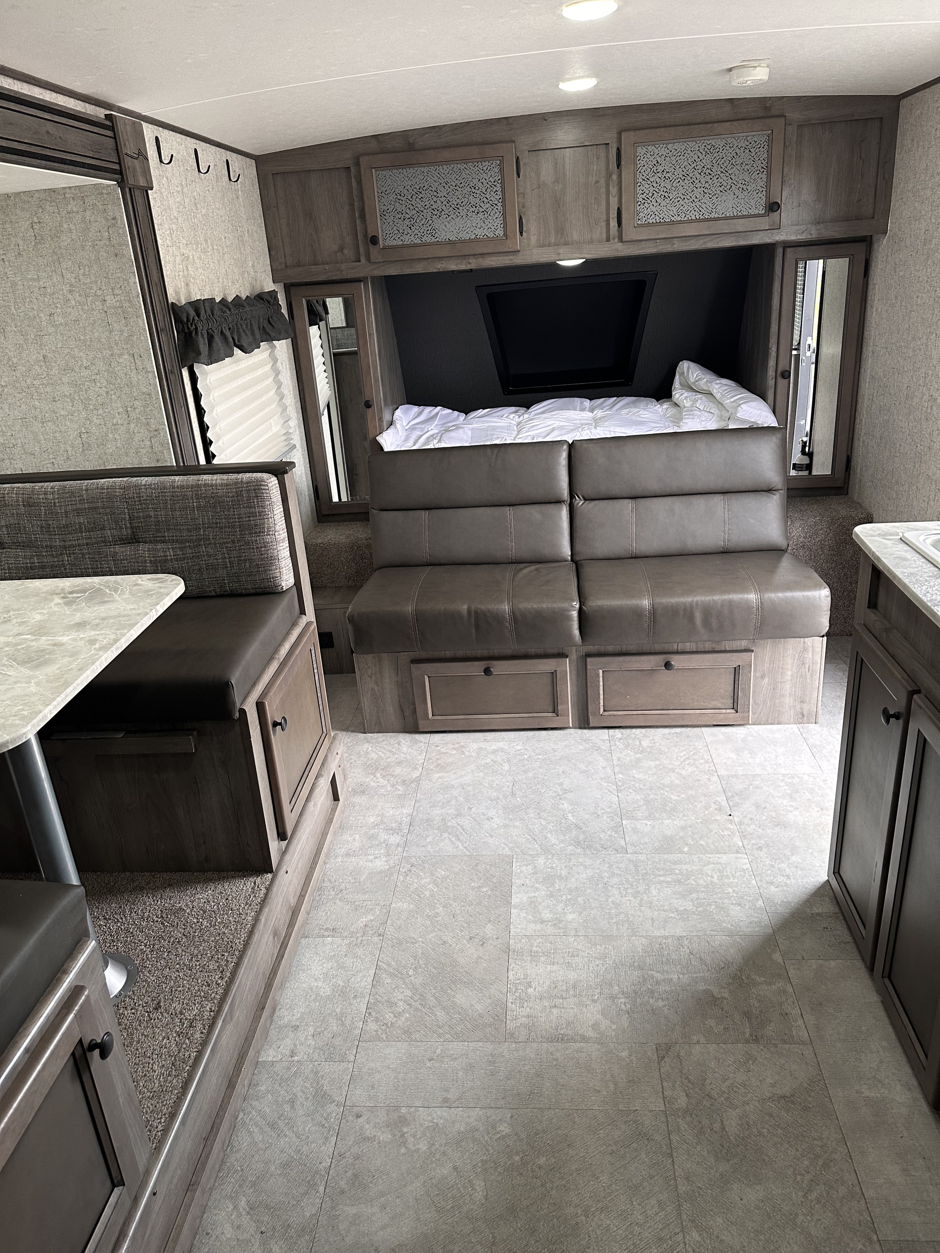 RV rental interior showcasing a dinette, a convertible sofa bed, and light tile flooring in this cozy travel trailer.. Coachmen Apex Nano 2020