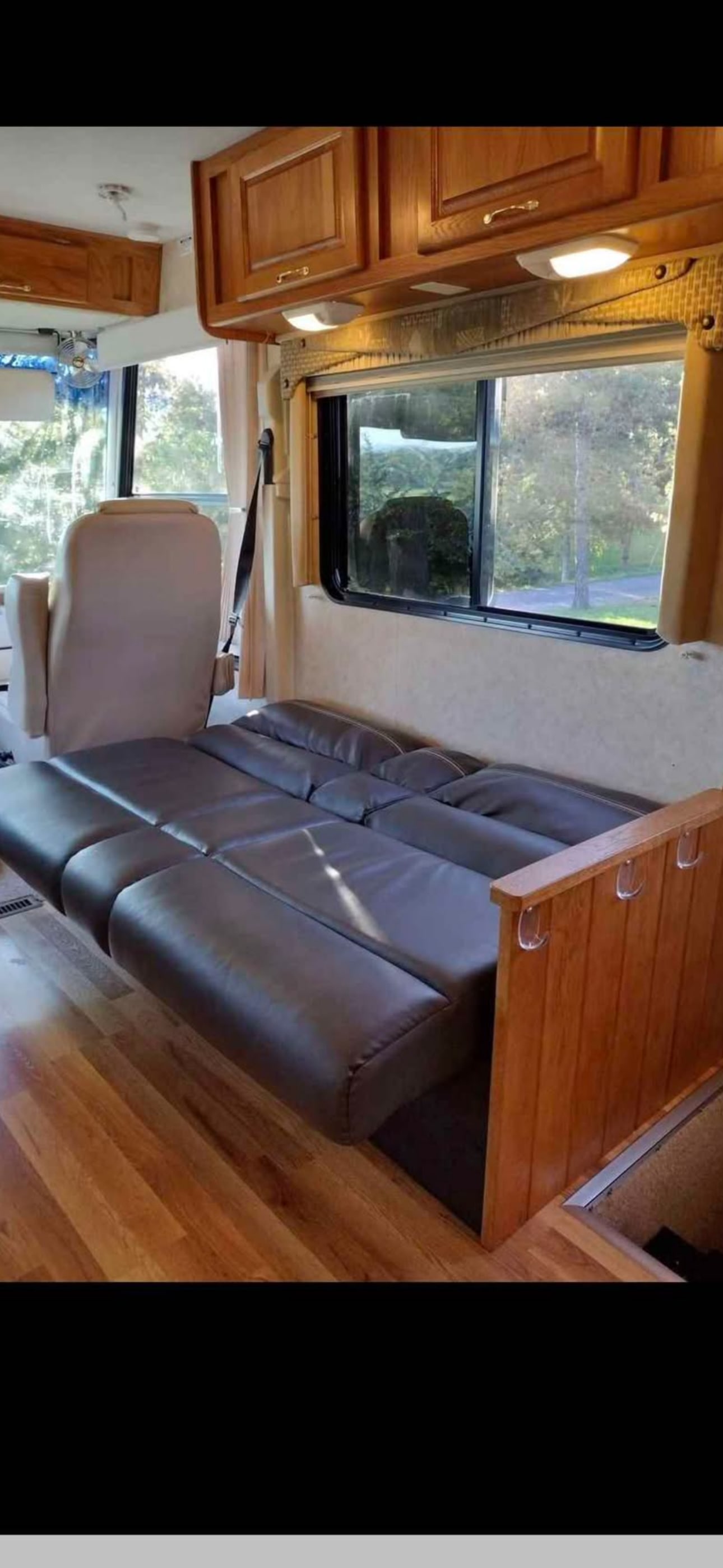 RV rental interior: cozy convertible sofa-bed, wood floor, and scenic window view. Perfect for your next adventure.. Ford 1F6NF3S740A06630 2004