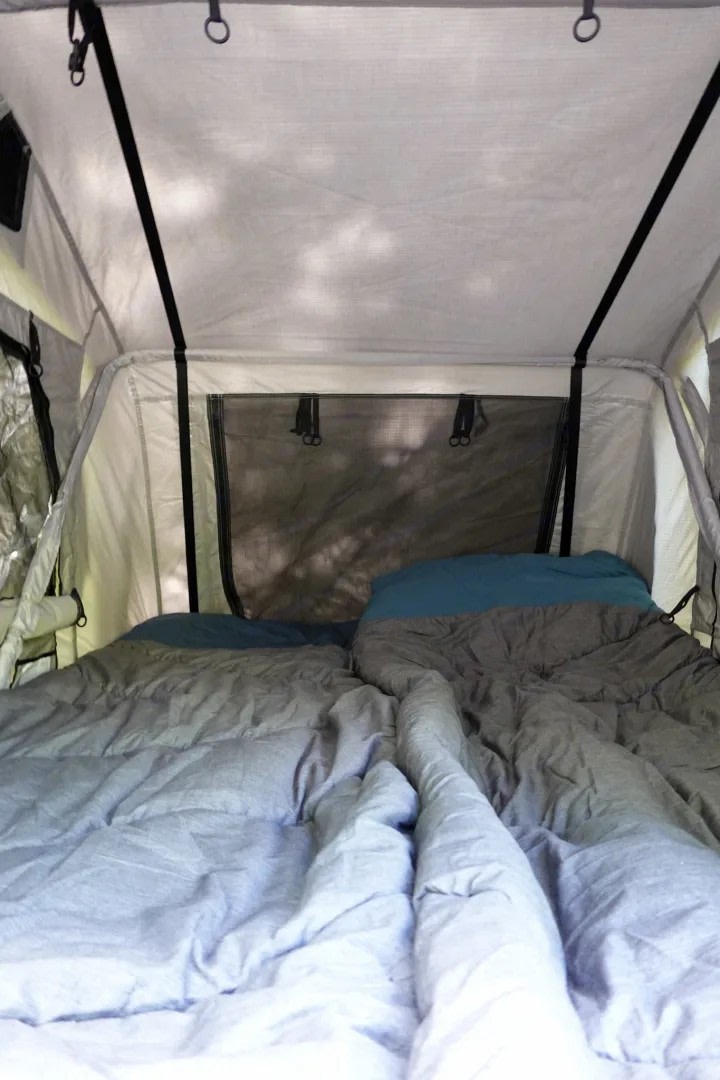Inside this RV rental, a cozy sleeping area features two individual beds with pillows, a mesh window, and a fabric ceiling.. Ford Mazda 2010