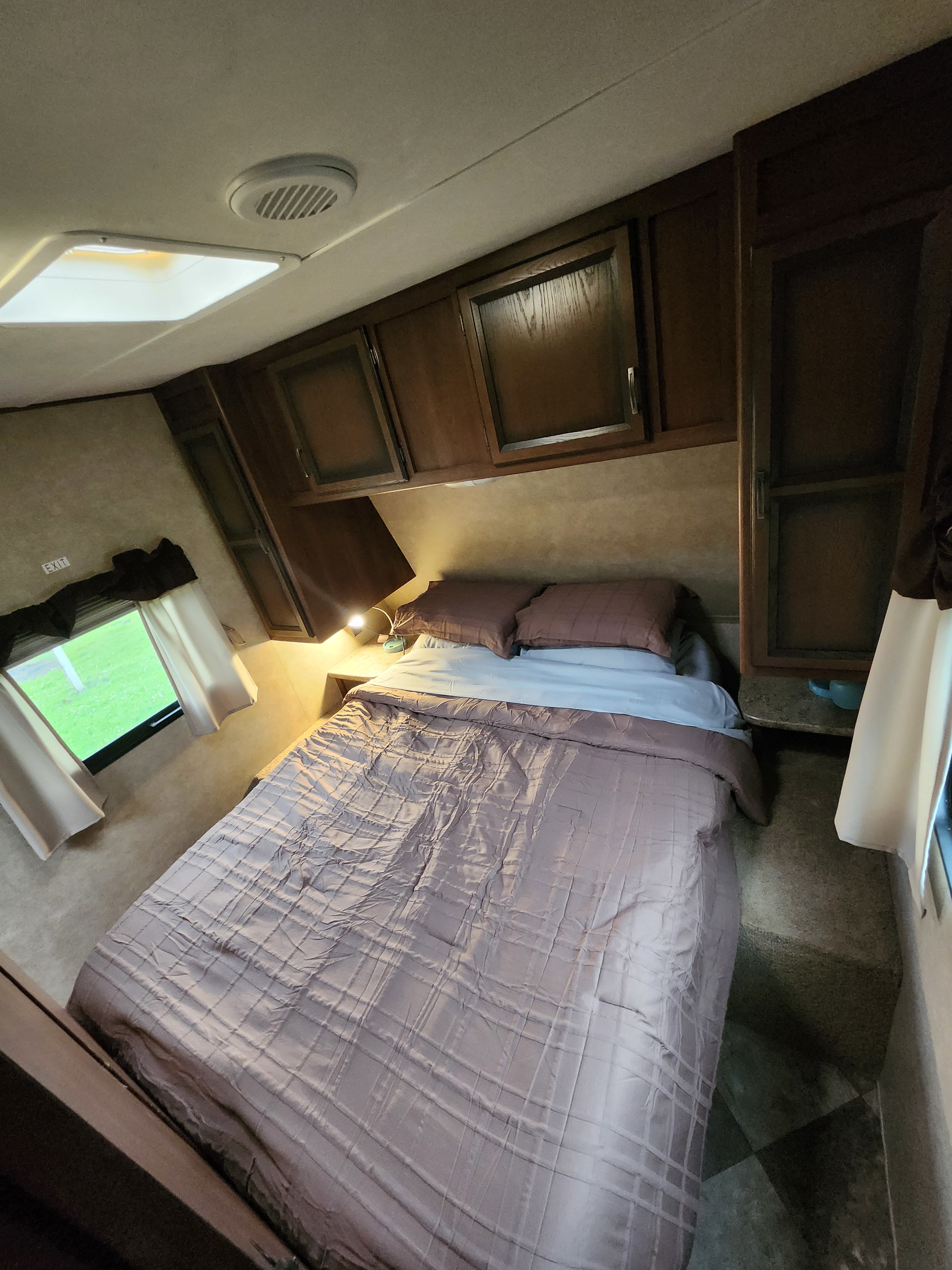 Cozy RV rental bedroom interior with a comfortable bed, overhead cabinets, and a bright window looking outside.. 4V0TC2620FJ005216 Crossroads 2015