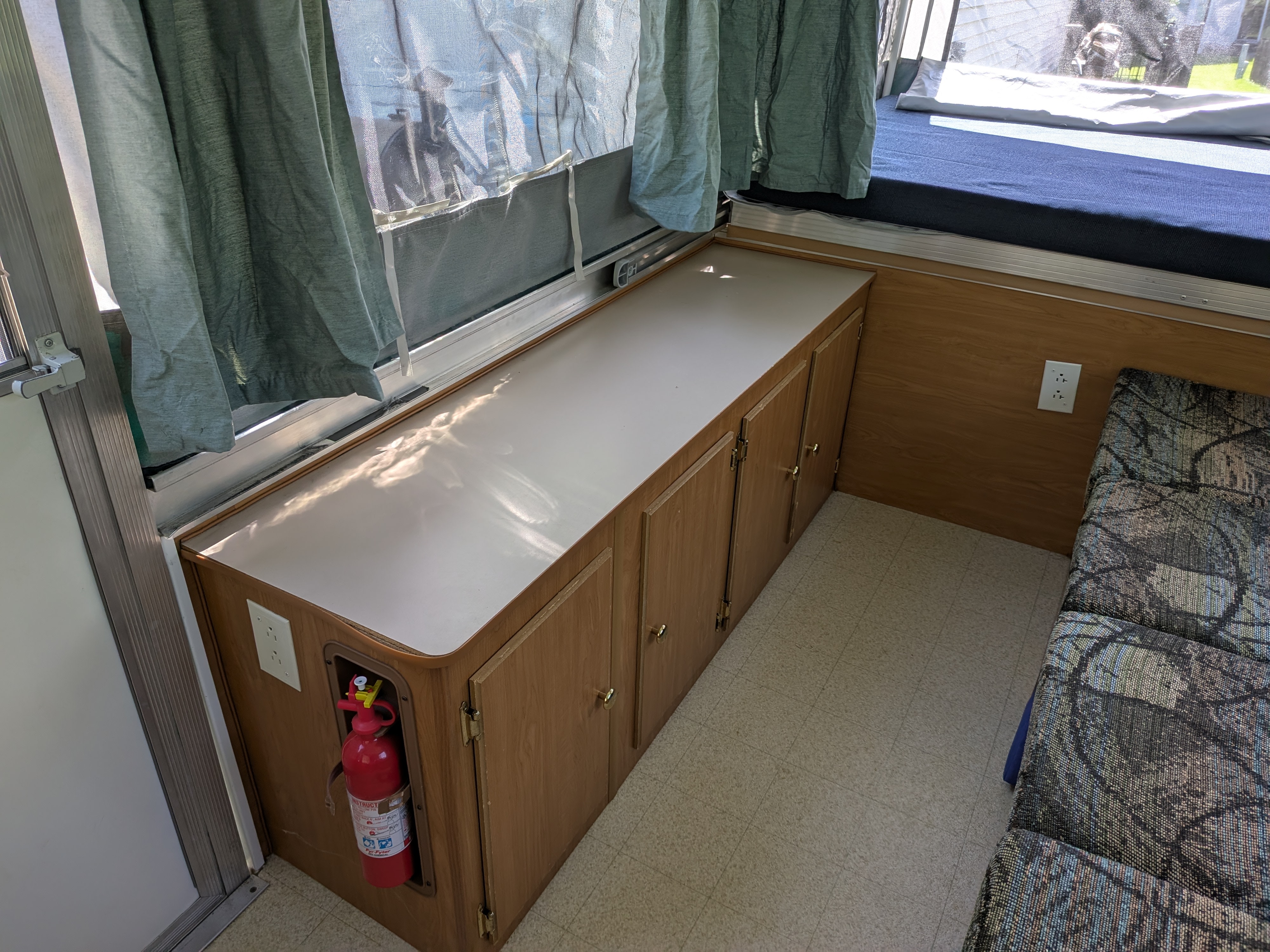 Explore this rv rental's organized interior, featuring storage cabinets, a bed, and safety essentials like a fire extinguisher.. Coleman Destiny Sedona 2002