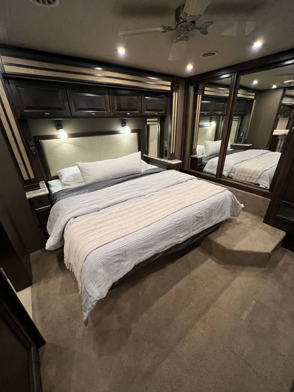 Luxurious RV rental bedroom. Features a comfortable bed, overhead cabinets, mirrored wardrobes, and plush carpet for travel comfort.. Allegro Allegro Red 2019
