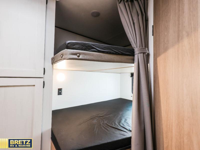 RV rental bunk beds: A compact sleeping area with two dark mattresses, a privacy curtain, and reading light. Ideal for family adventures.. Keystone RV Other 2026
