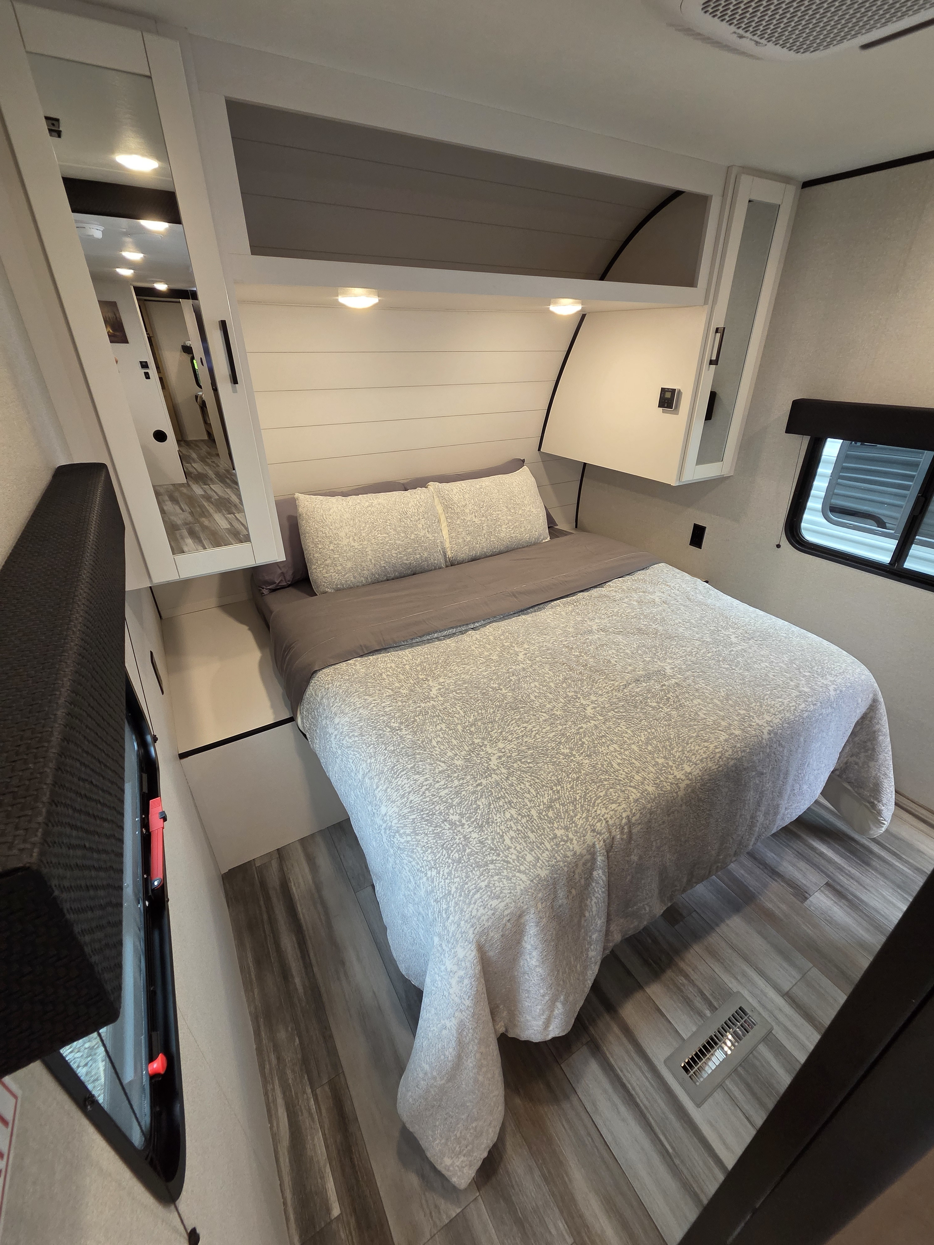 Cozy RV rental bedroom with a patterned bed, plank headboard, mirrored wardrobe, and window. Ideal for your next trip!. Jayco Jay Flight SLX 2025