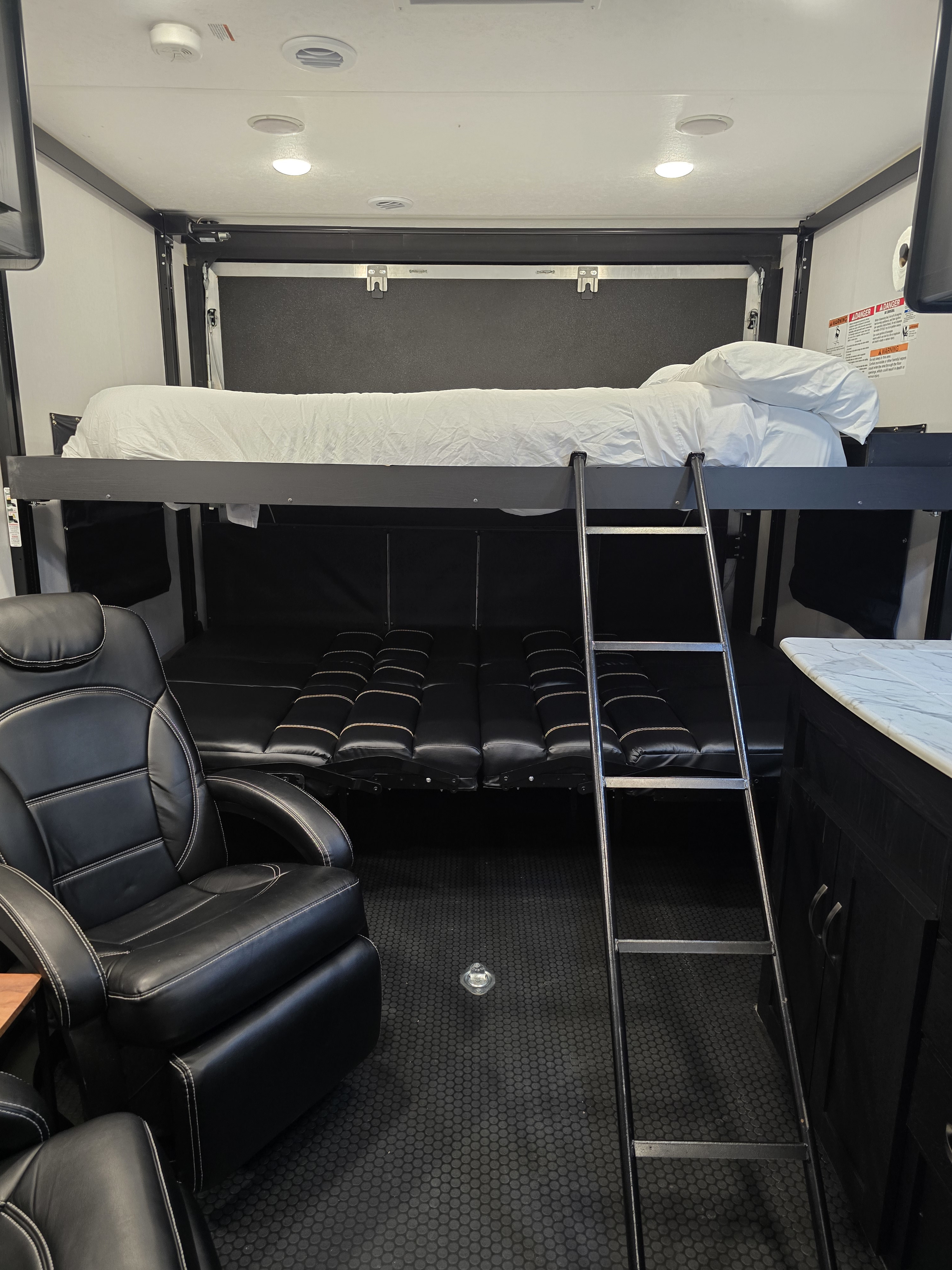 Modern RV rental interior with comfy recliner chairs, versatile bunk beds, and durable rubber flooring for mobile living.. Coachmen Adrenaline 2022
