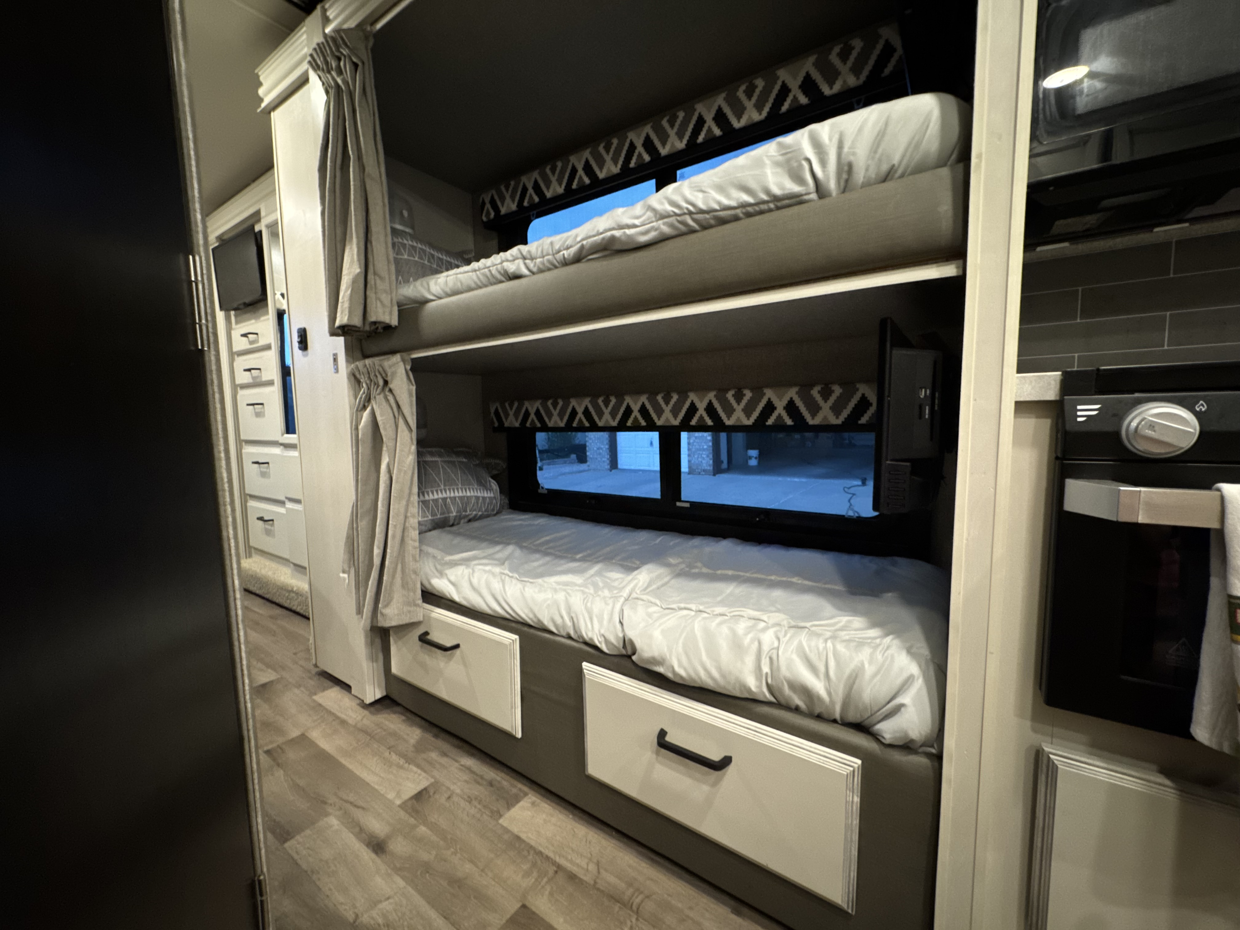 Inside this RV rental, dual bunk beds offer cozy sleeping with individual windows, curtains, and a TV on the bottom bunk.. Jayco Greyhawk 2021