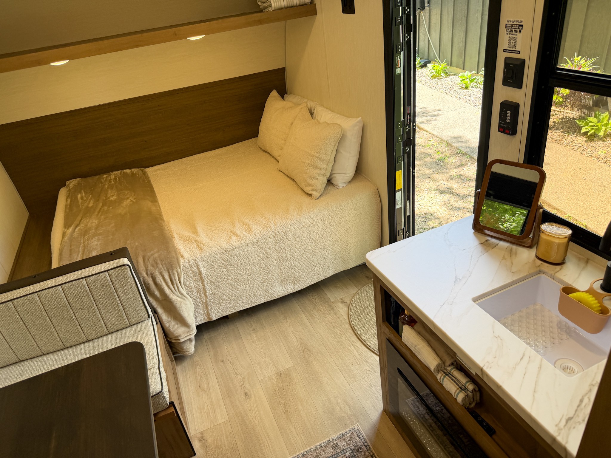 A cozy, modern RV rental interior features a bed, dining area, and compact kitchenette with a sink, viewed from above.. Forest River Cherokee Wolf Pup 2025