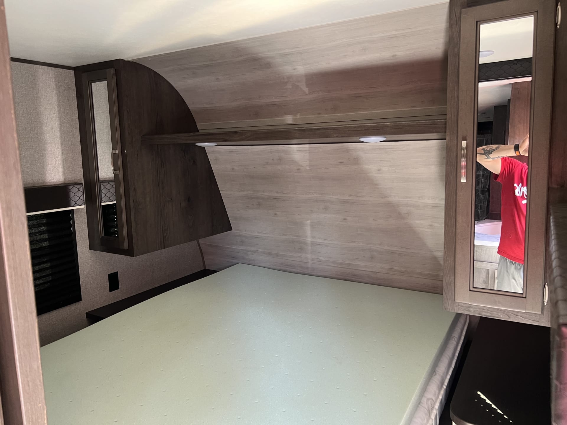 Cozy rv rental bedroom with light green foam mattress, wood-grain walls, and illuminated storage cabinets for a comfy travel experience.. Jayco Jay Flight SLX 2021