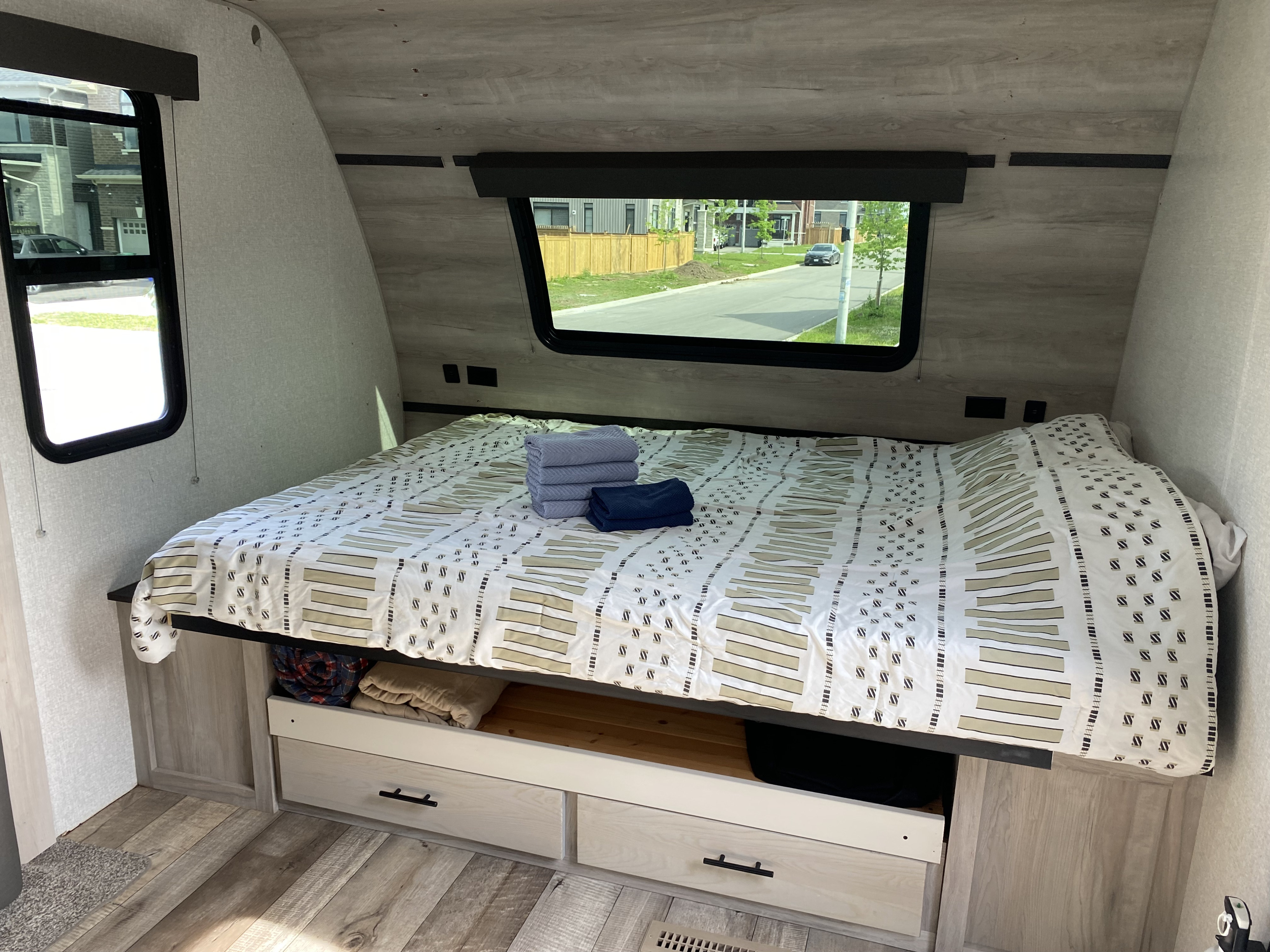 Inside an RV rental, a comfy bedroom features a patterned bed, under-bed storage, and windows. Great for travel trailer trips.. KZ Connect SE 2021