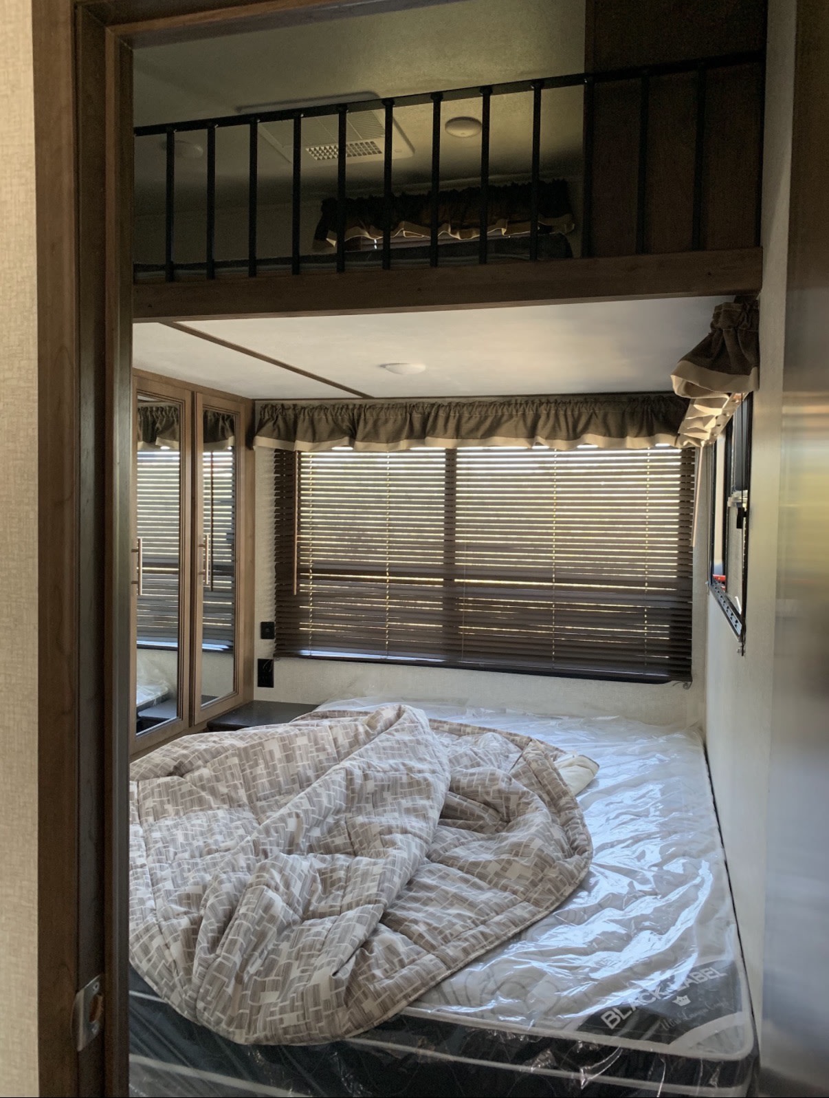This RV rental features a cozy bedroom with a new plastic-covered mattress, patterned comforter, blinds, mirrored closet, and overhead loft.. Keystone RV Cougar 2020