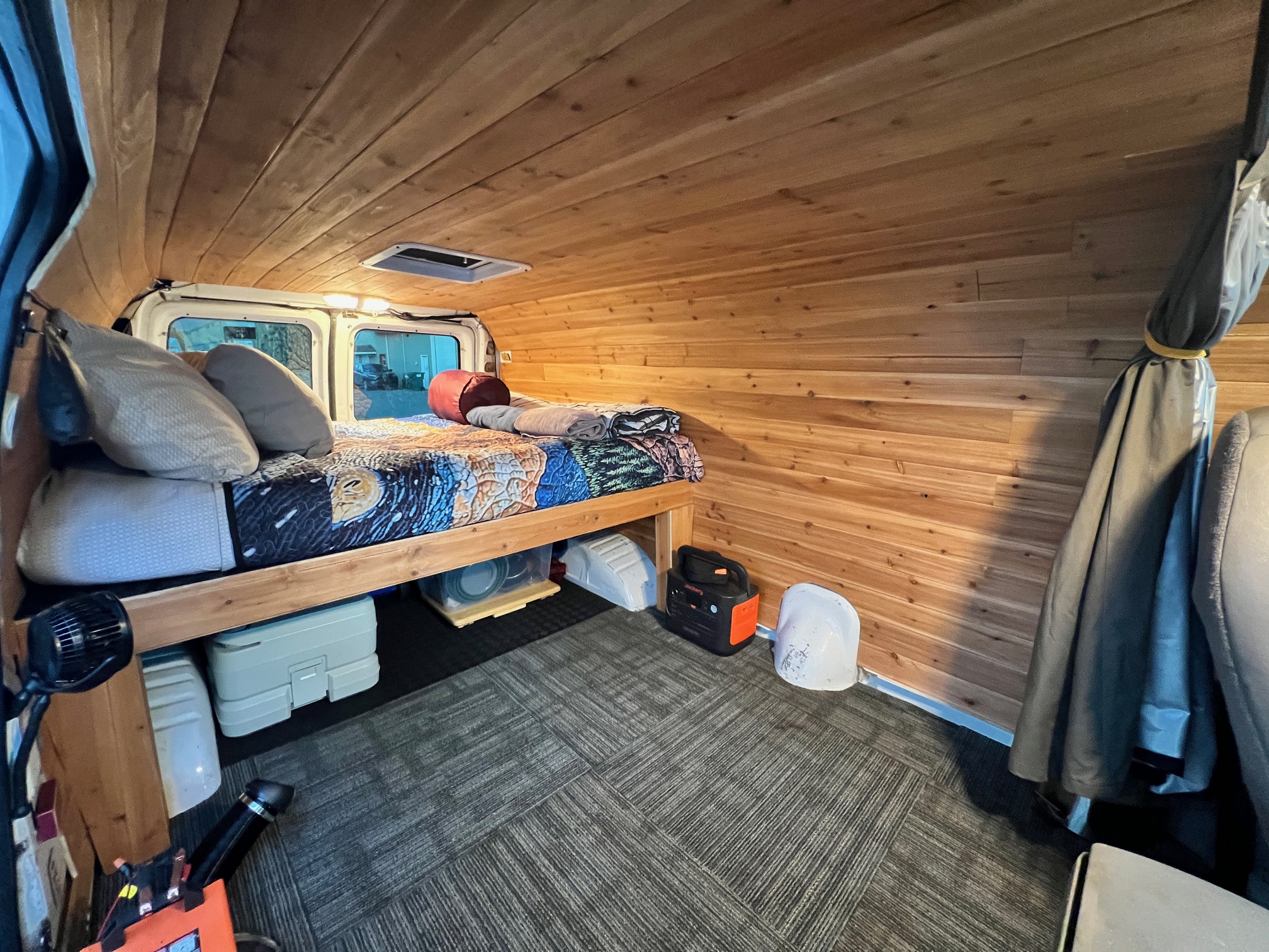 A cozy RV rental's wooden interior, featuring a bed, storage under, and soft lighting for comfortable travel.. Ford Econoline 150 1997