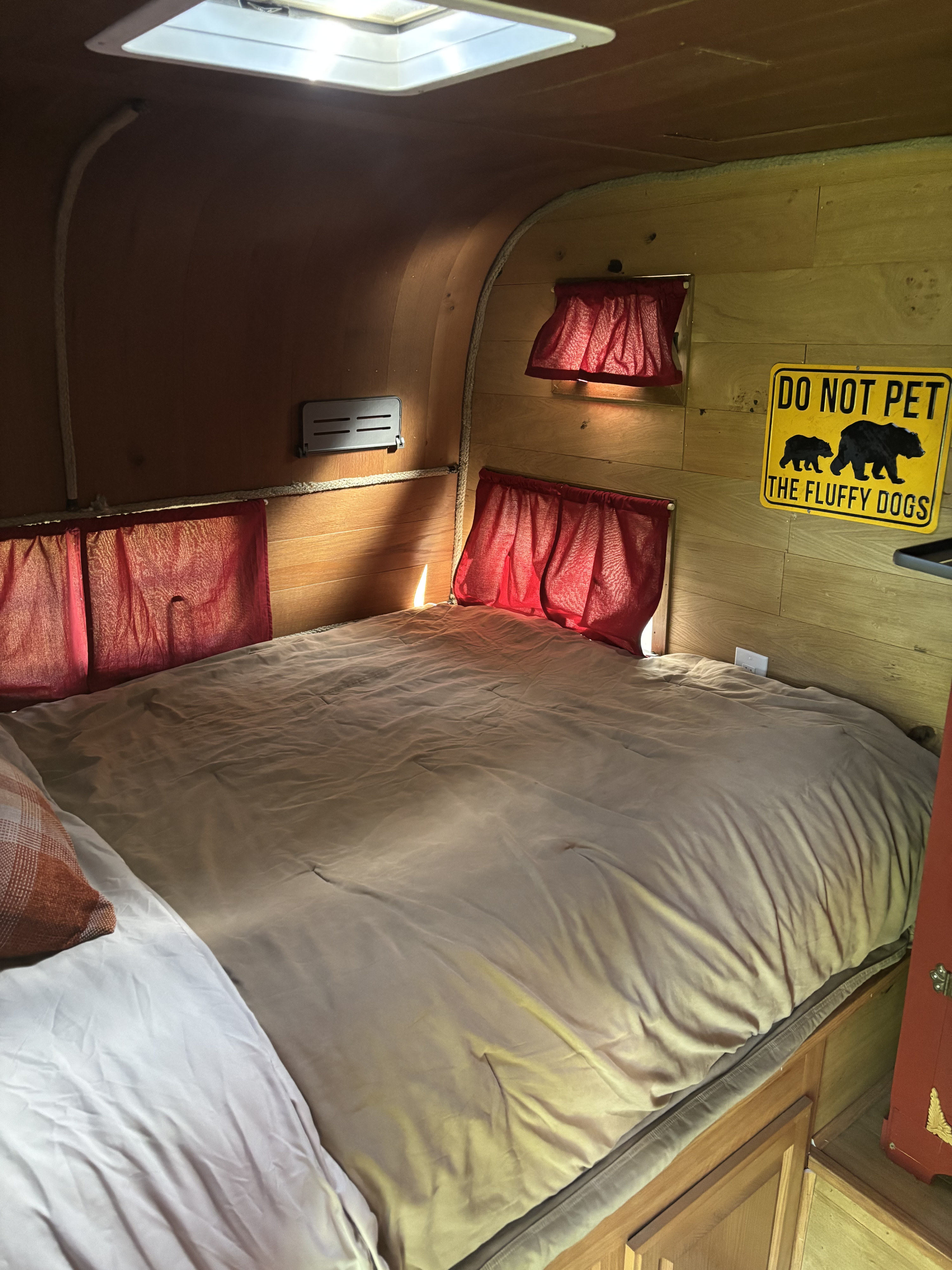 Cozy RV rental bedroom with wood paneling, comfortable bed, and a humorous "Do Not Pet The Fluffy Dogs" sign.. Silver Eagle 17 1966