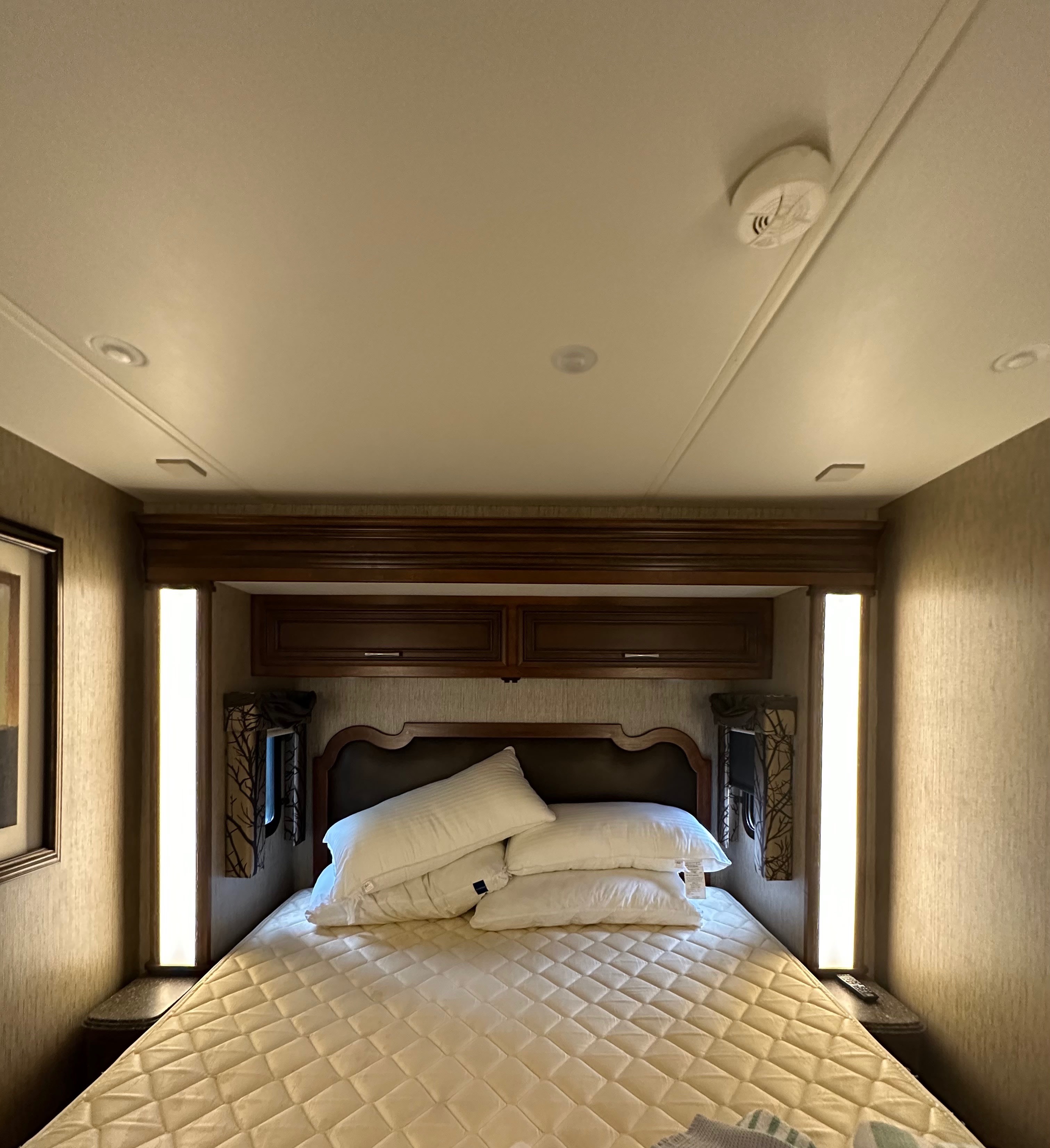 Cozy RV rental bedroom with a large bed, decorative headboard, overhead storage, and vertical lighting panels, ideal for a comfortable stay.. Newmar Canyon Star 2016