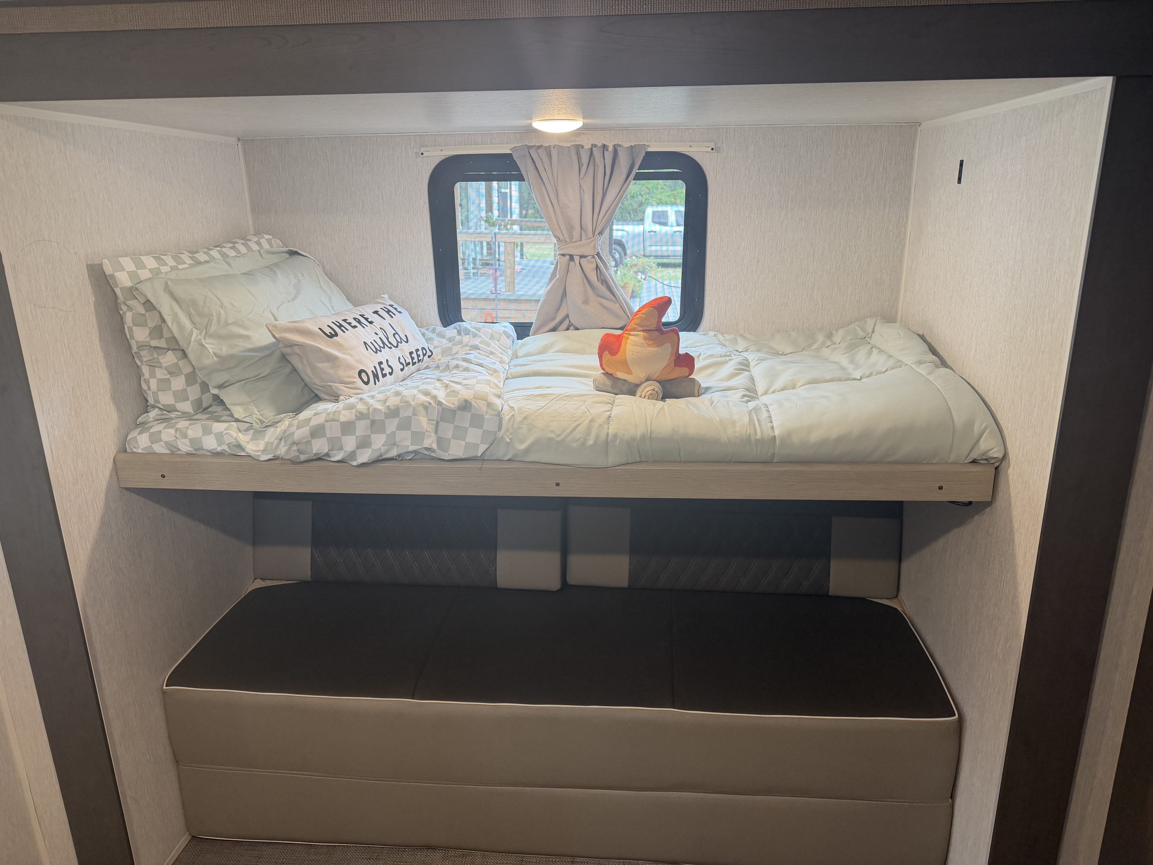 Cozy bunk beds in an RV rental, complete with a window view and a plush campfire toy for a fun, inviting sleeping space.. Forest River Salem Platinum 2024