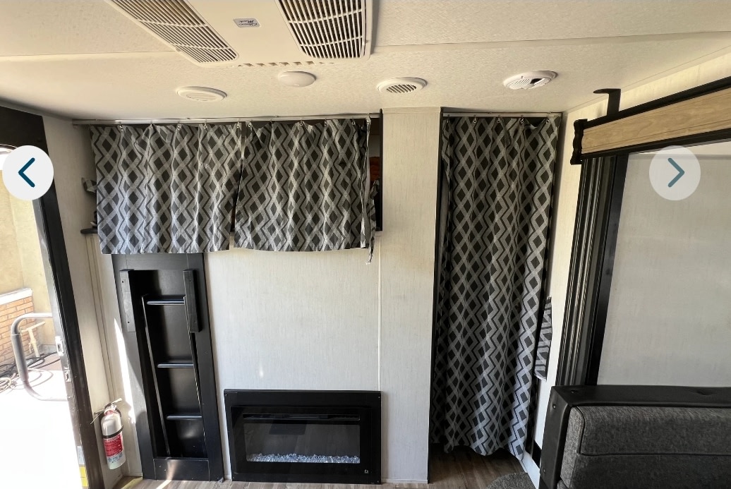Cozy RV rental interior with patterned curtains, electric fireplace, and ladder, highlighting functional design.. Forest River Cherokee 2022