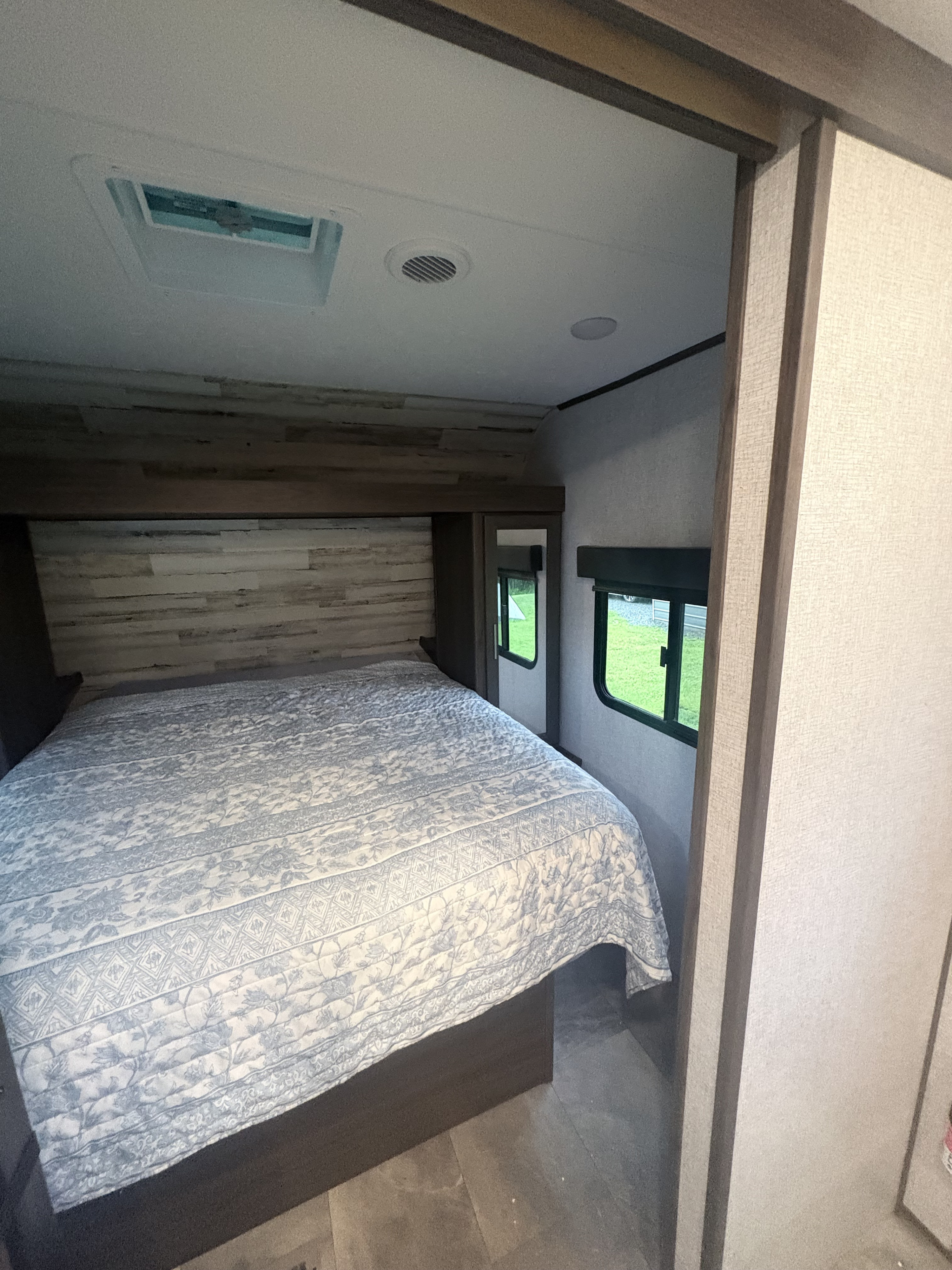 Cozy RV rental bedroom with a comfy bed, wood paneling, and windows offering views. Perfect for your next adventure.. Dutchmen Kodiak SE 2021