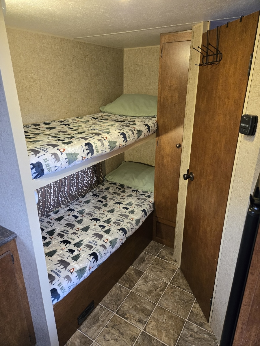 An RV rental's cozy sleeping area features two bunk beds with nature-themed bedding and an adjacent storage closet.. Spree Escape 2016