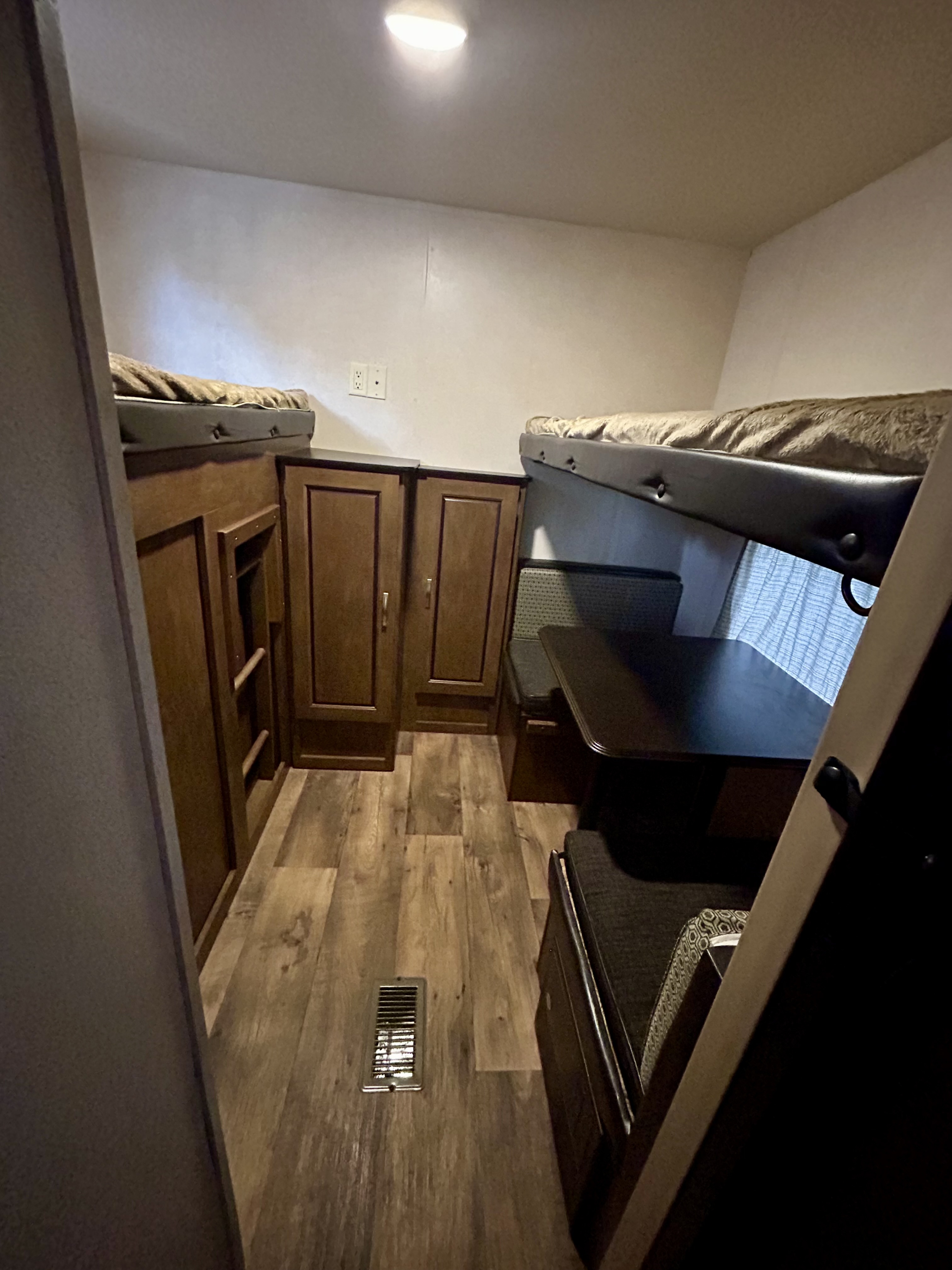 Compact RV rental interior featuring bunk beds, a dinette with table, and wood-look storage cabinets. Ideal for travel.. Forest River Salem 2017