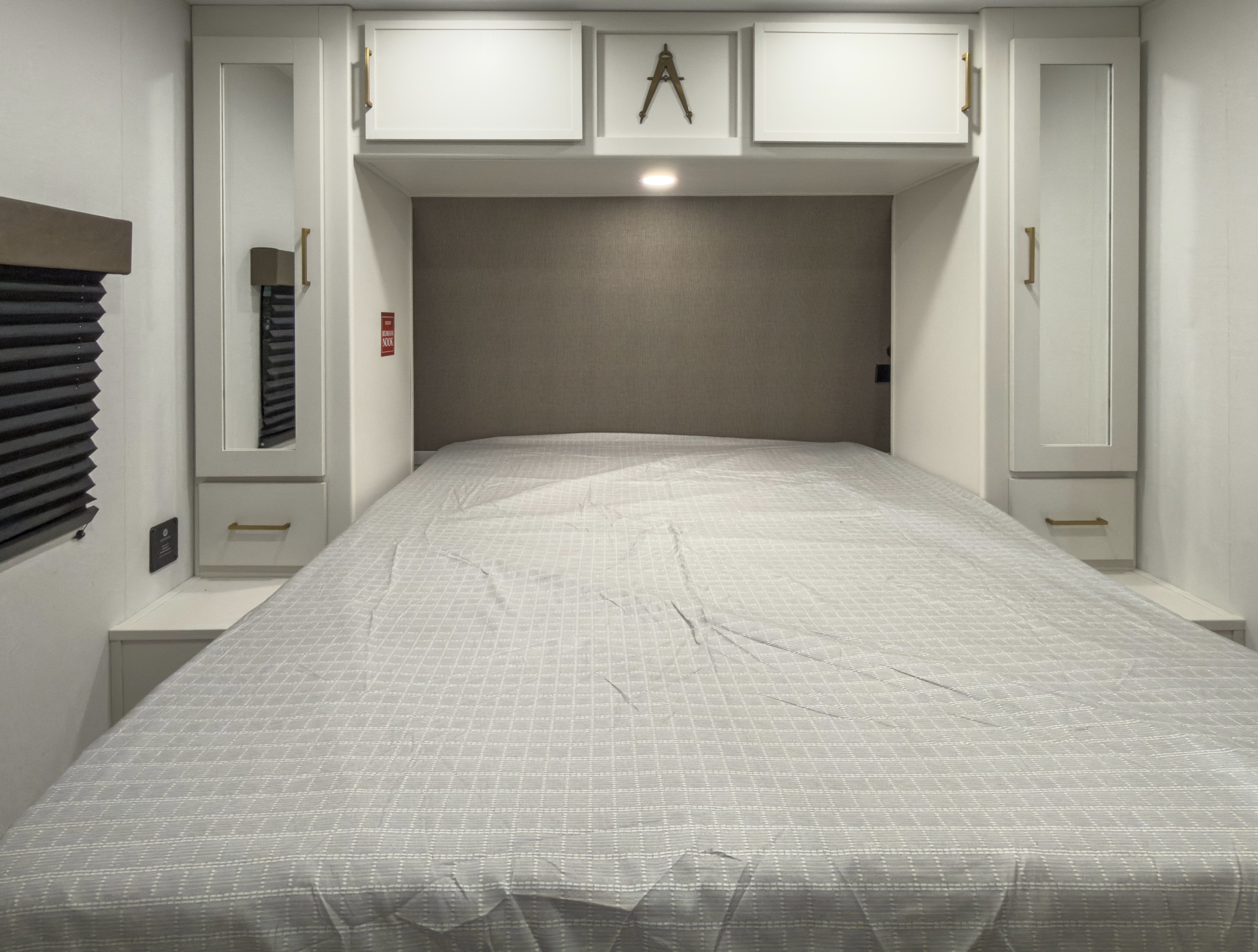 Comfortable RV rental bedroom with modern white cabinets, bedside storage, and a cozy patterned comforter.. Grand Design Transcend 2027