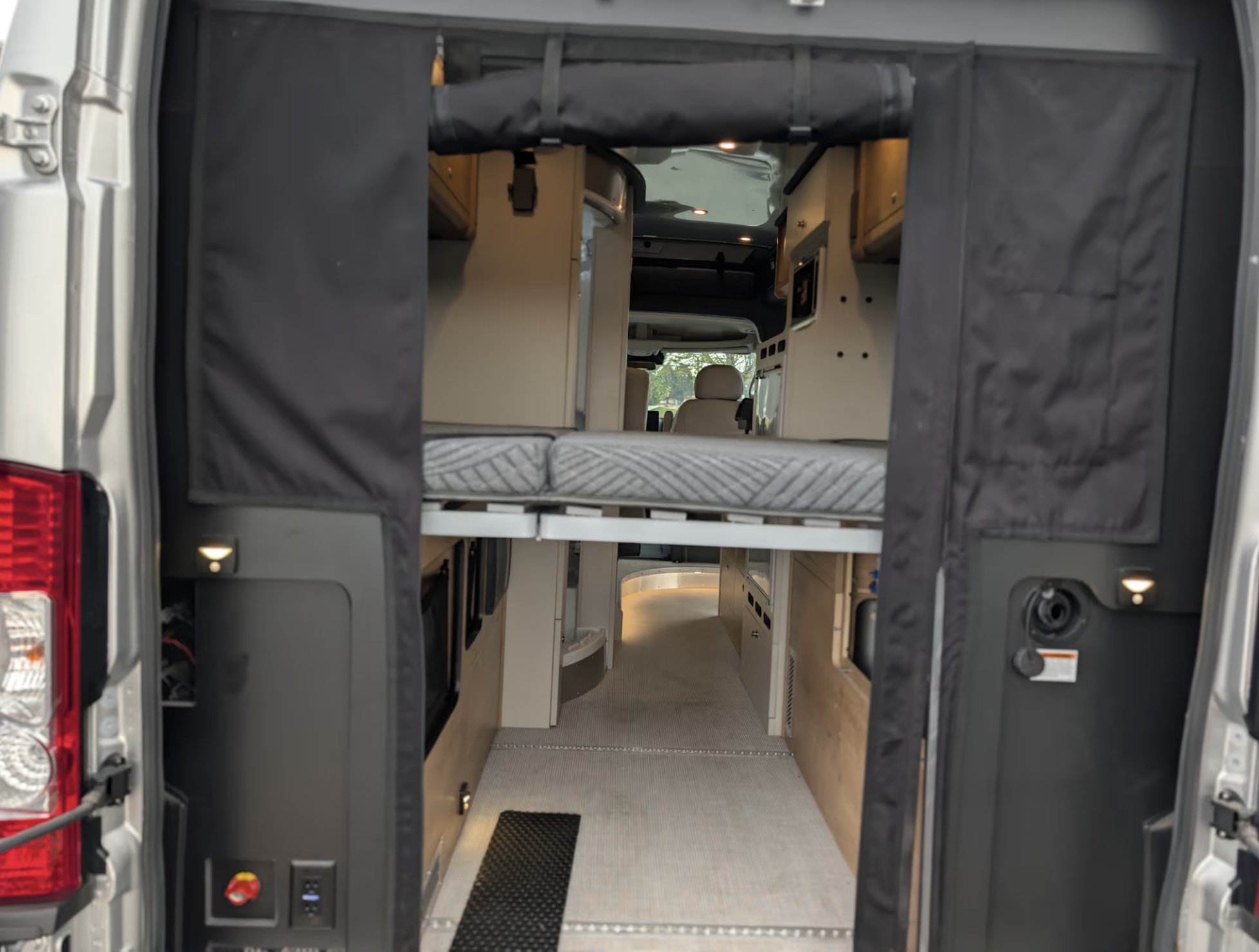 Inside a stylish RV rental van with a raised bed and ample storage, ready for your adventure.. Airstream Rangeline 2024