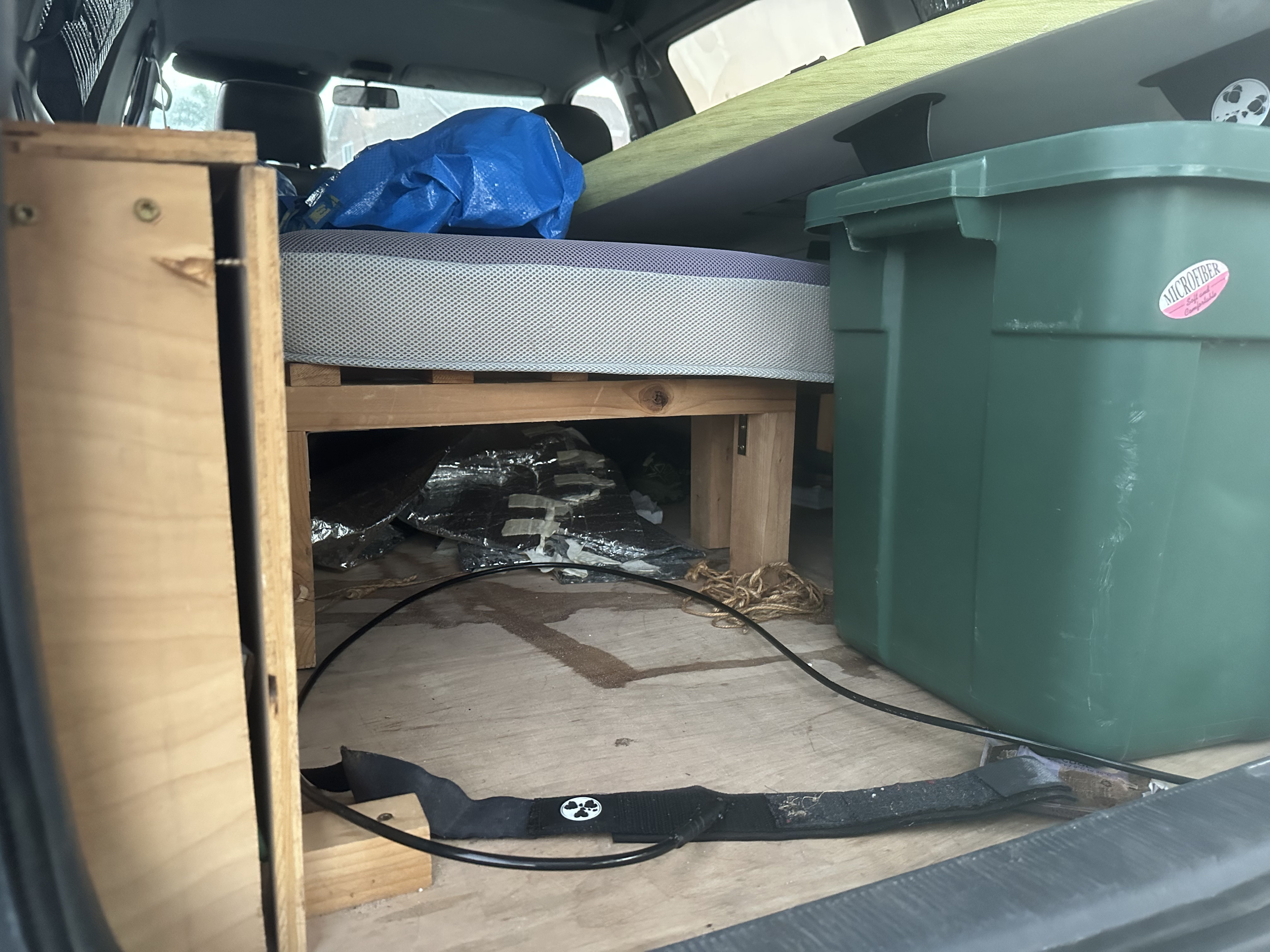 RV rental interior: DIY bed, green storage, and surfboard, set up for a campervan adventure.. Toyota Previa 1996