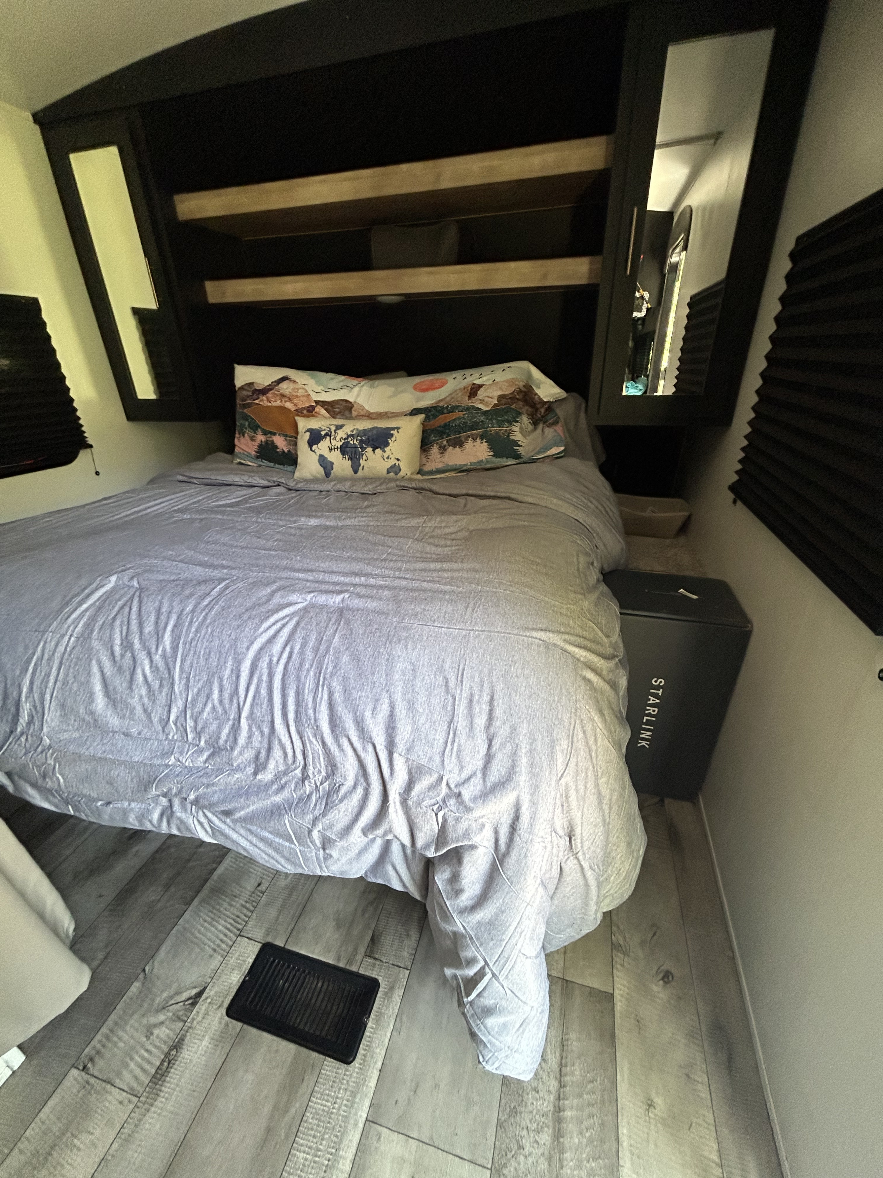 Comfortable RV rental bedroom showcasing a bed with gray linens, travel-themed pillows, mirrored storage, and a Starlink box.. Keystone RV Springdale 2022