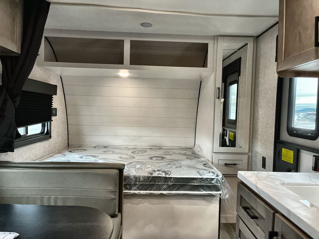 Inside a new rv rental: a cozy bed, dinette, compact kitchen, and mirrored closet are ready for travel.. Starcraft Autumn Ridge 2025