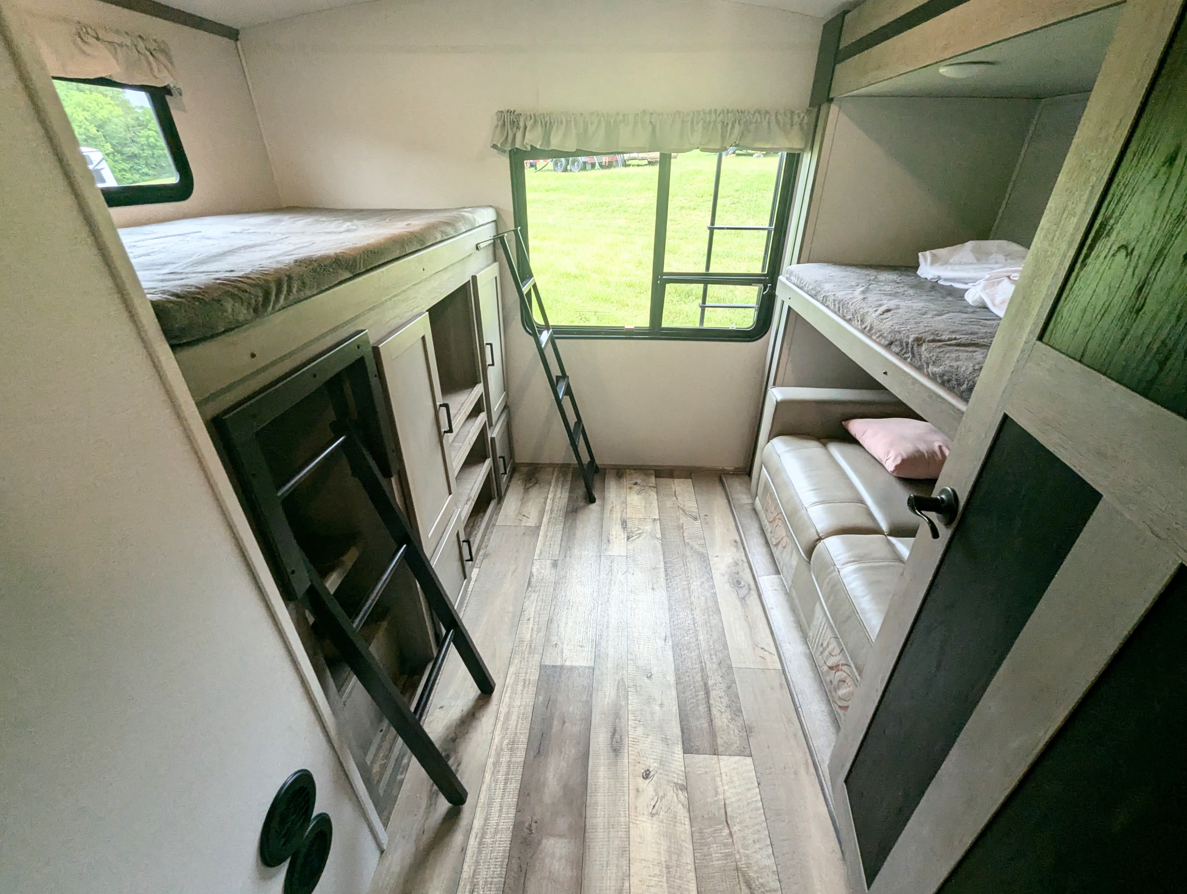 This rv rental shows a sleeping area with bunk beds, sofa, storage, and a window, ideal for family travel.. Keystone Outback 2021