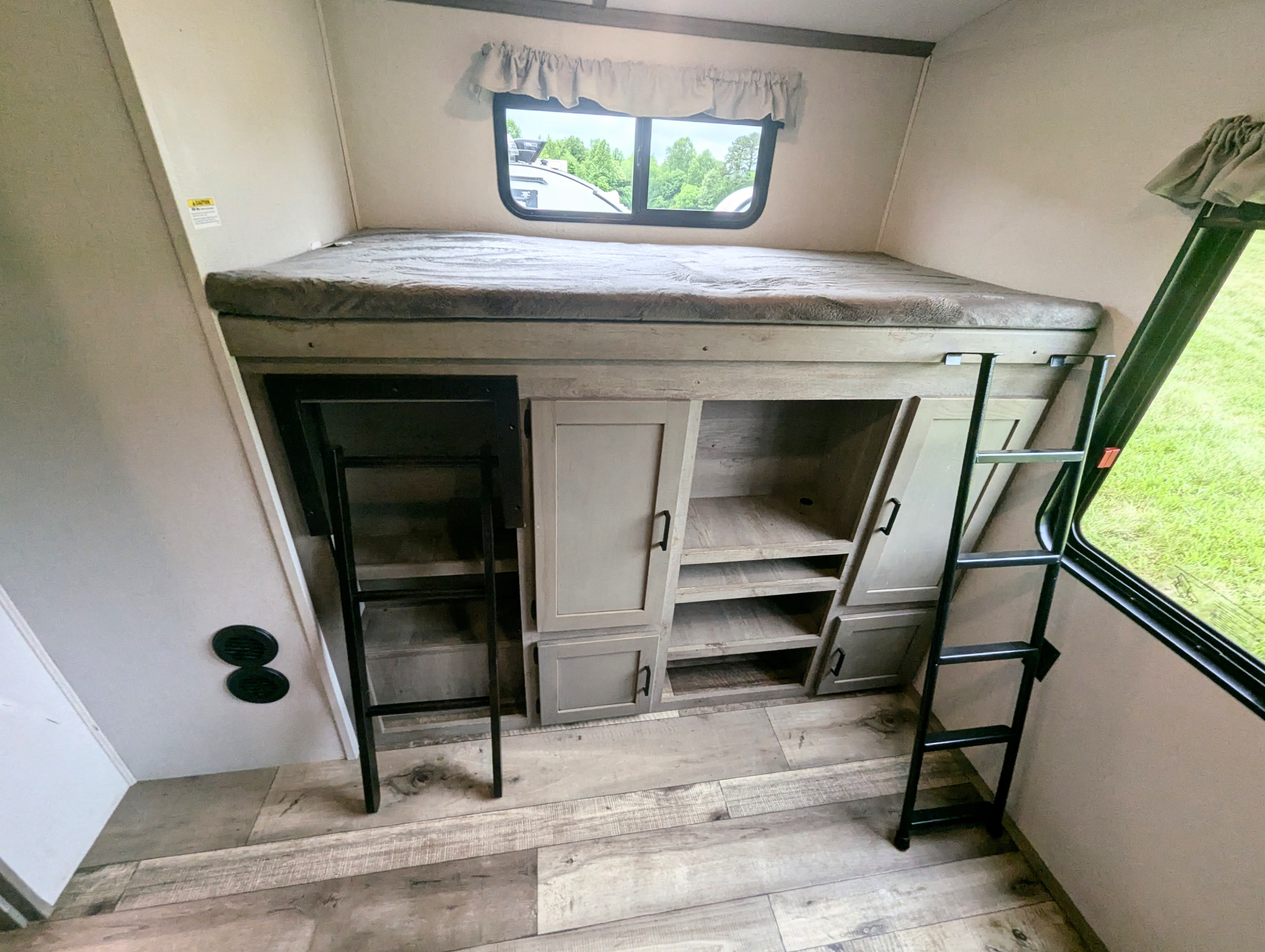 Interior of an RV rental: bunk bed with two ladders, built-in storage, and a scenic window.. Keystone Outback 2021