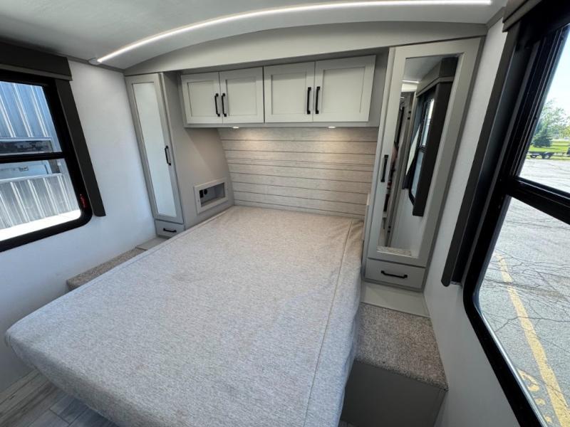 Modern RV rental bedroom. Features a comfy bed, overhead cabinets, wardrobes, and bright windows, perfect for travel.. Keystone RV Outback 2021