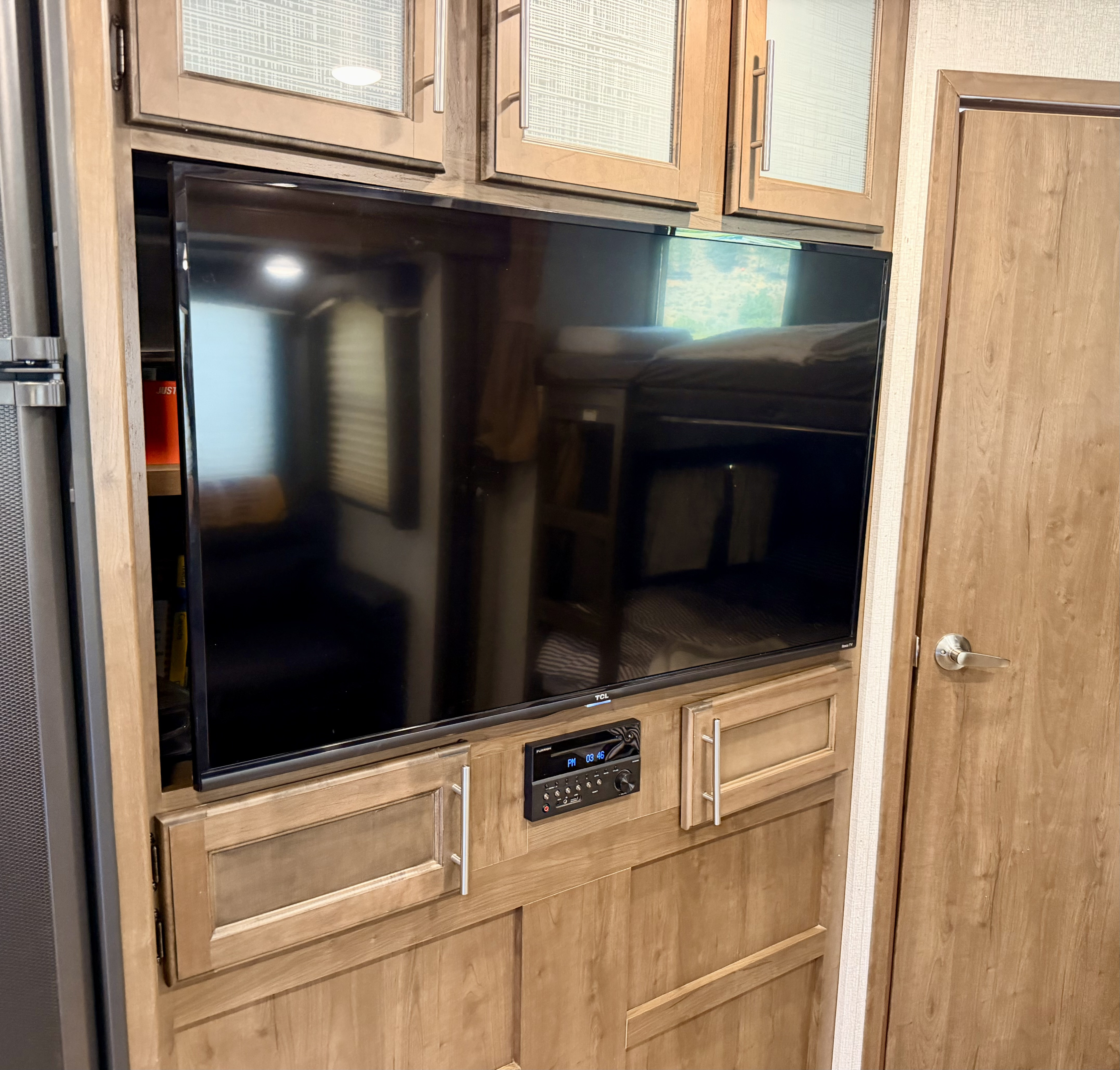 RV rental: Modern wood entertainment center with a TCL TV, Furrion stereo, and overhead cabinets. Comfortable interior space.. Keystone RV Cougar 2019
