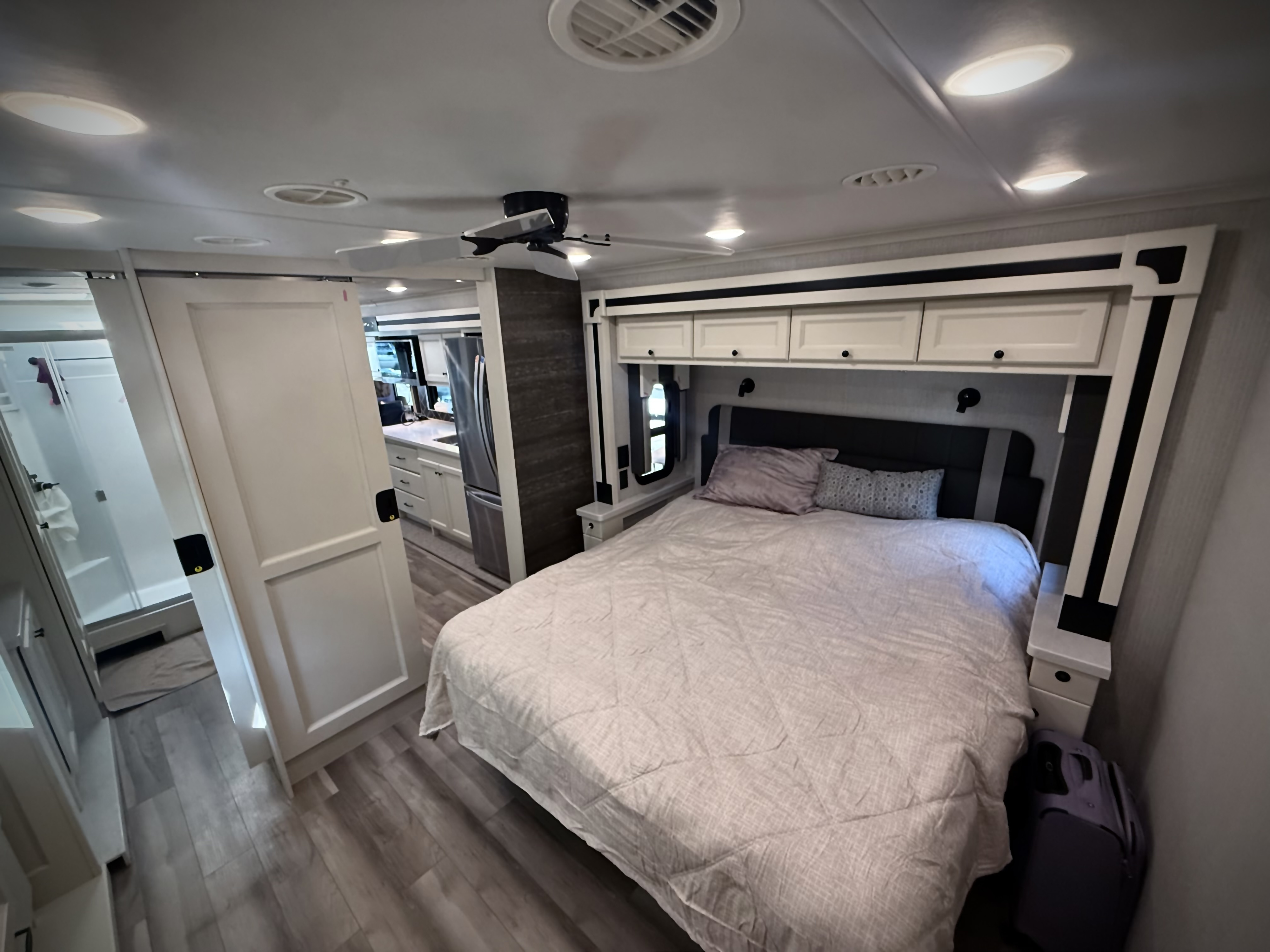 Inside a modern RV rental: a comfortable bedroom with a queen bed, overhead storage, and adjacent bathroom.. Allegro Allegro Open Road 2026