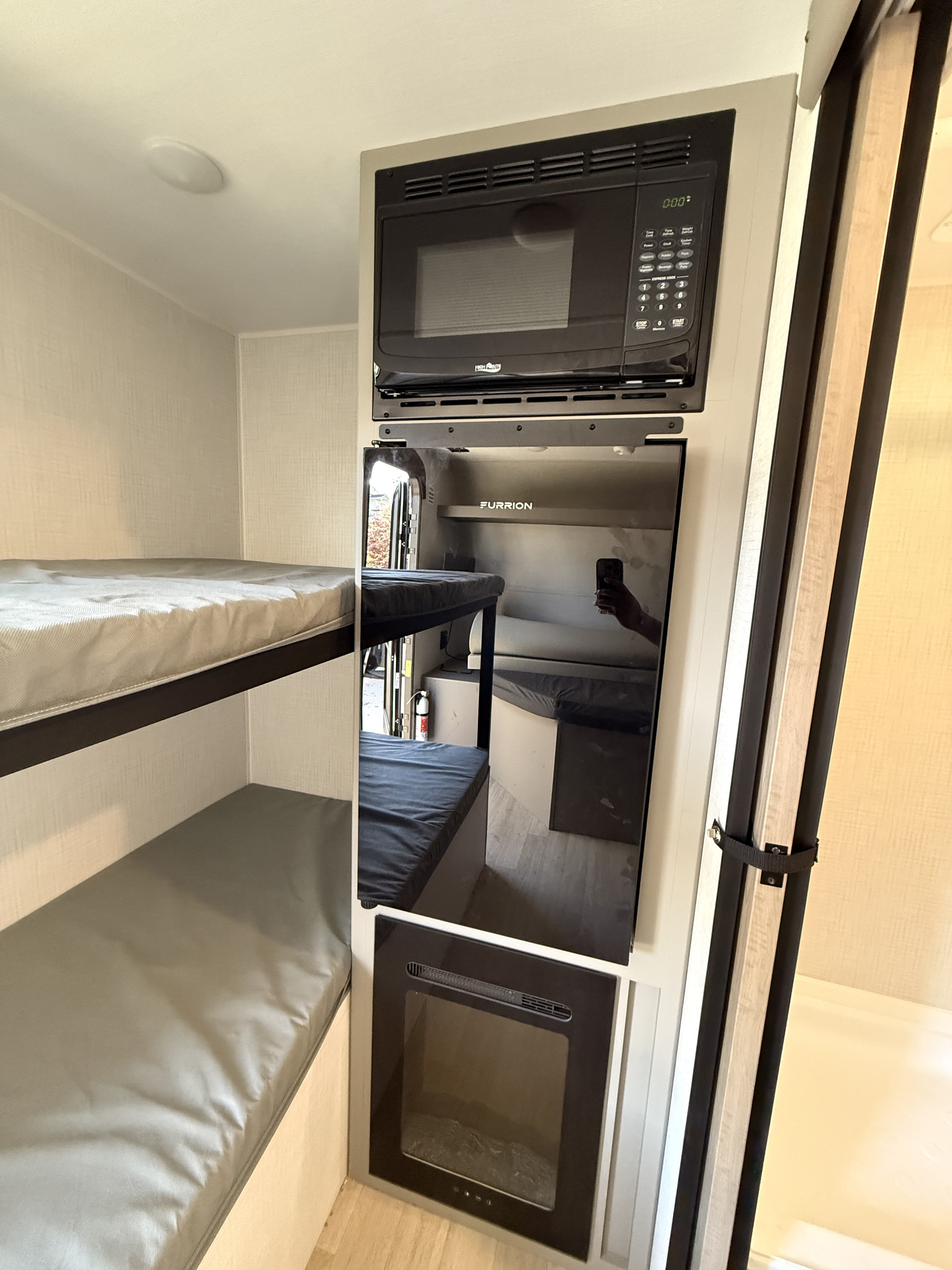 RV rental interior with compact bunk beds, a microwave, Furrion refrigerator, and electric fireplace for cozy travel.. Keystone RV Hideout 2026